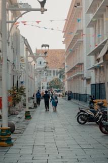 People stroll down a historic street lined with buildings.