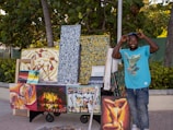 Artist stands proudly by his paintings for sale.