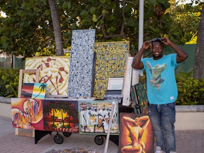 Artist stands proudly by his paintings for sale.