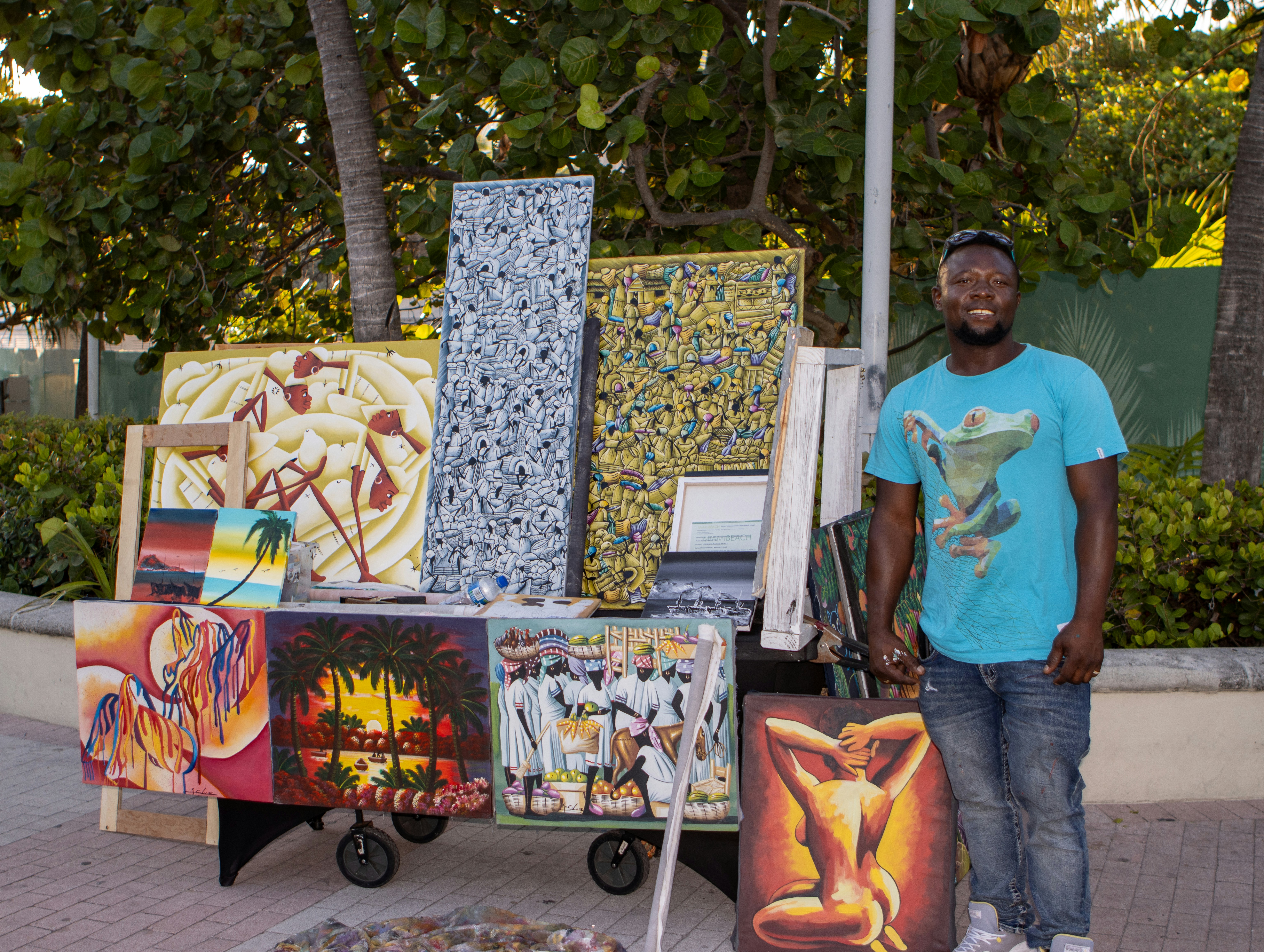 Artist stands near his colorful art for sale.
