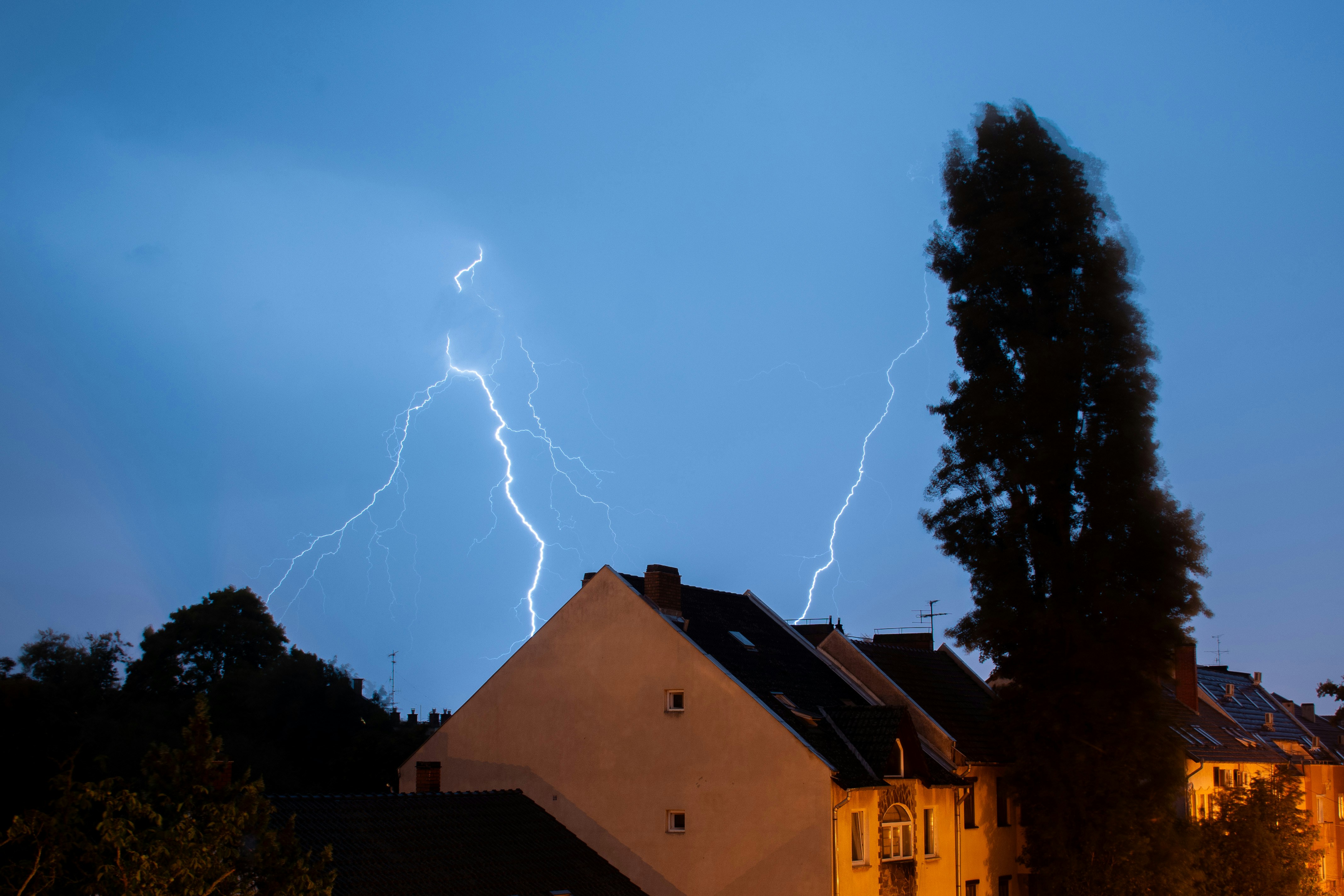 Lightning strikes over houses during a storm.