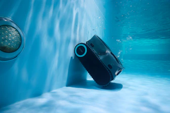 A robotic pool cleaner is working underwater.