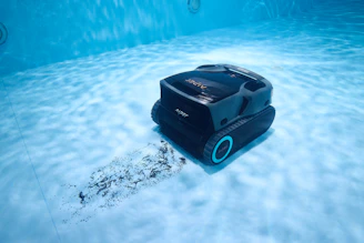 A robotic pool cleaner cleans underwater.