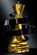 A golden queen chess piece with black swirl.