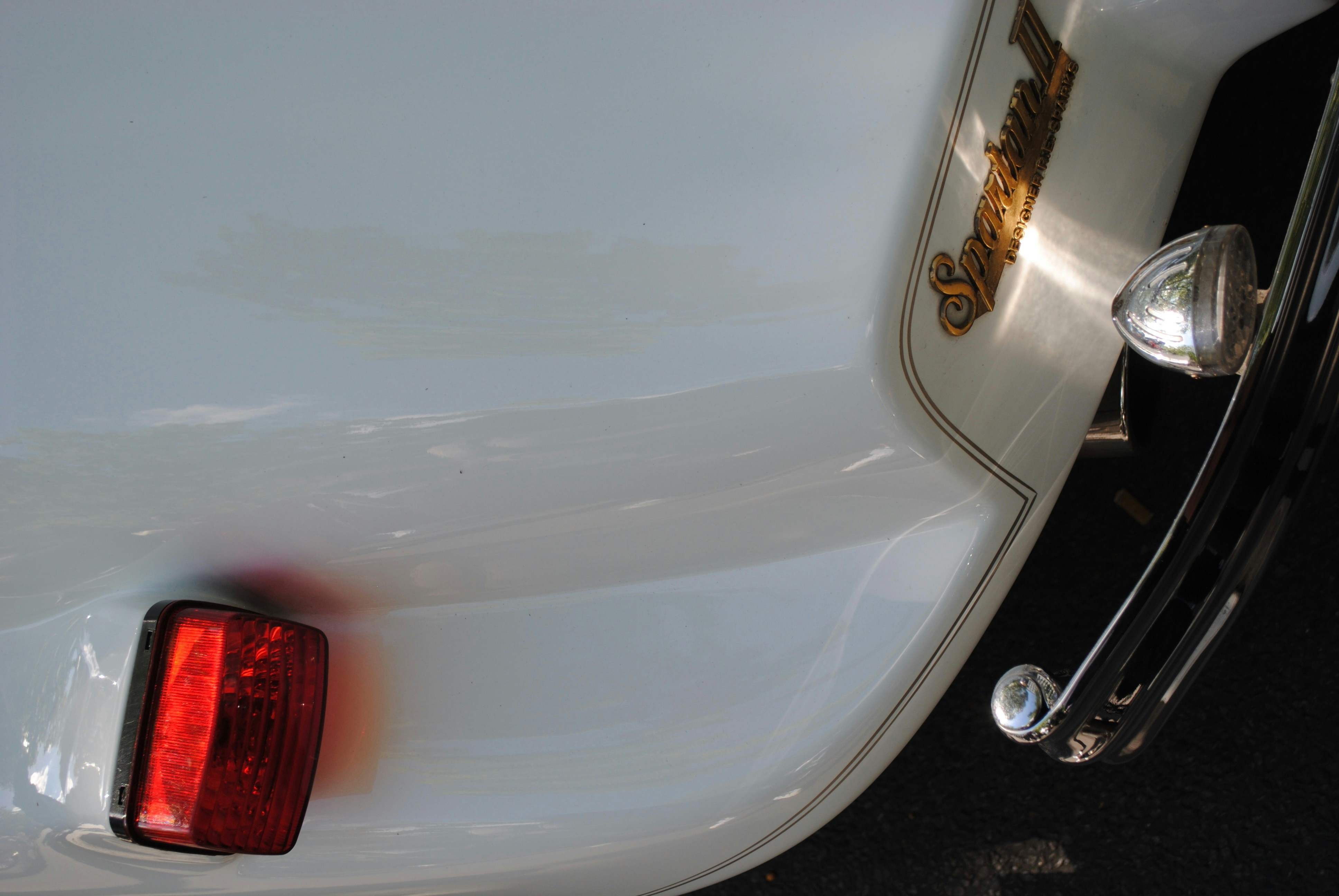 A vintage car's tail light and chrome details.