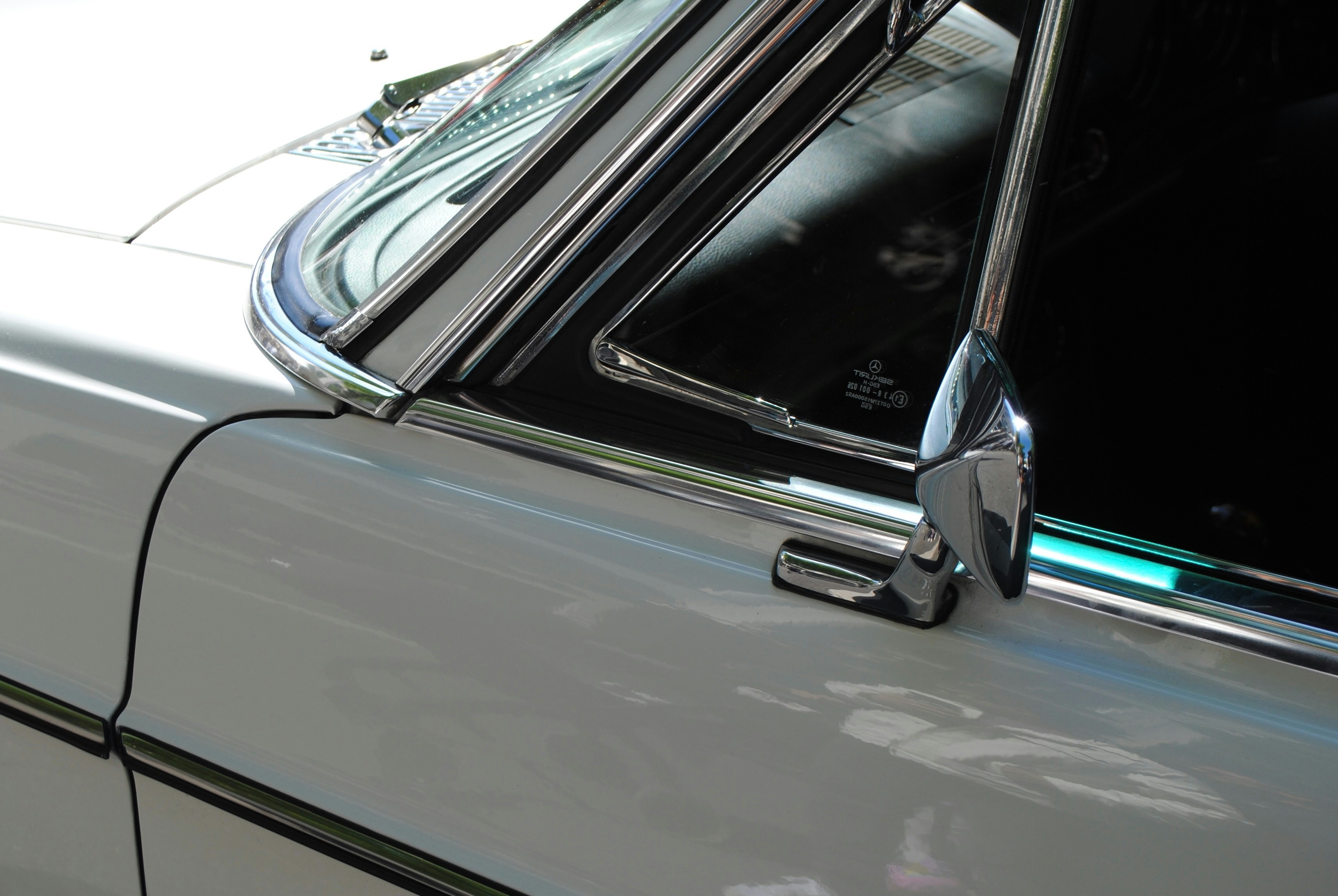 A white car's shiny chrome mirror.