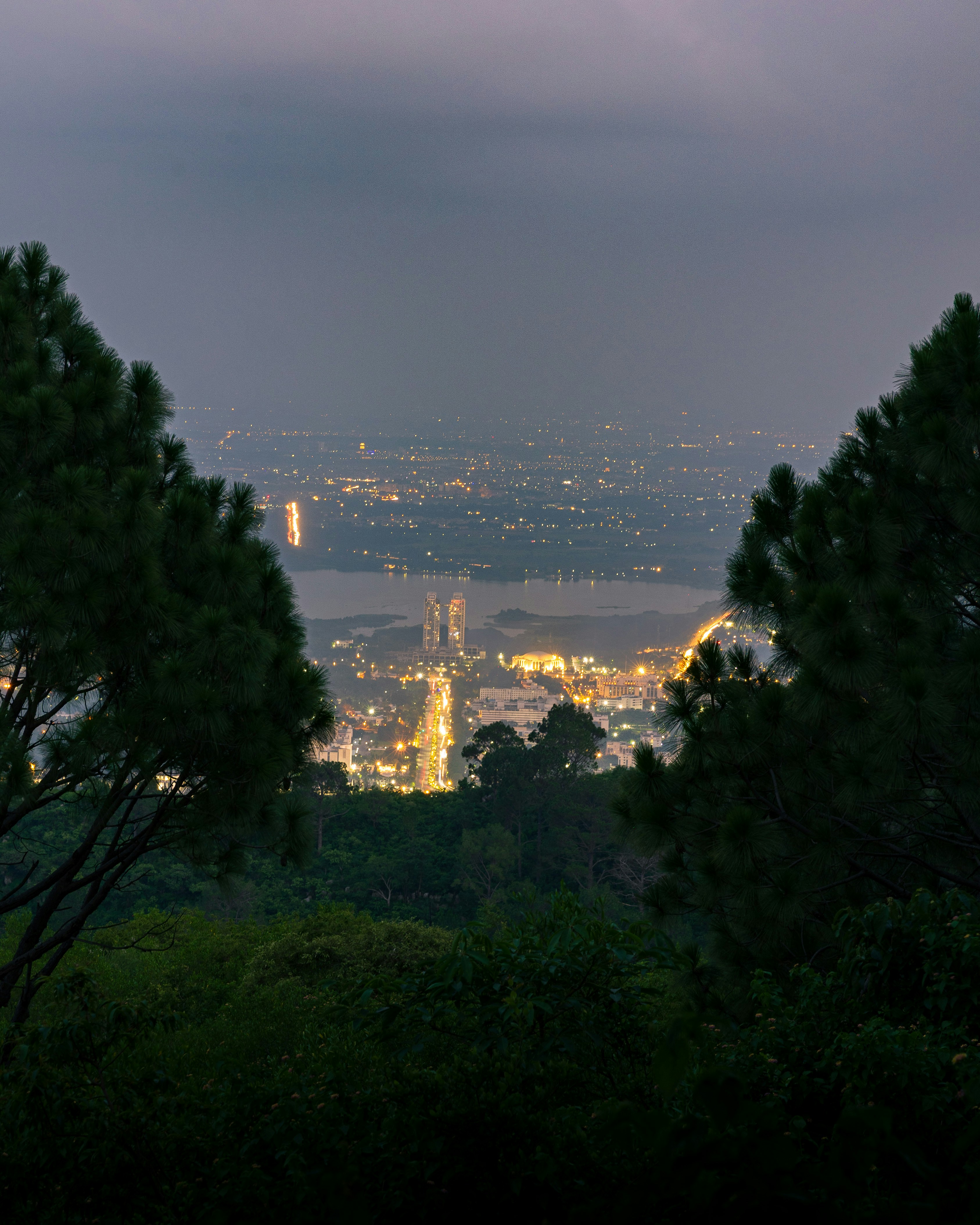 Die Lichter der Stadt erhellen ein Tal, das von Bäumen eingerahmt ist.