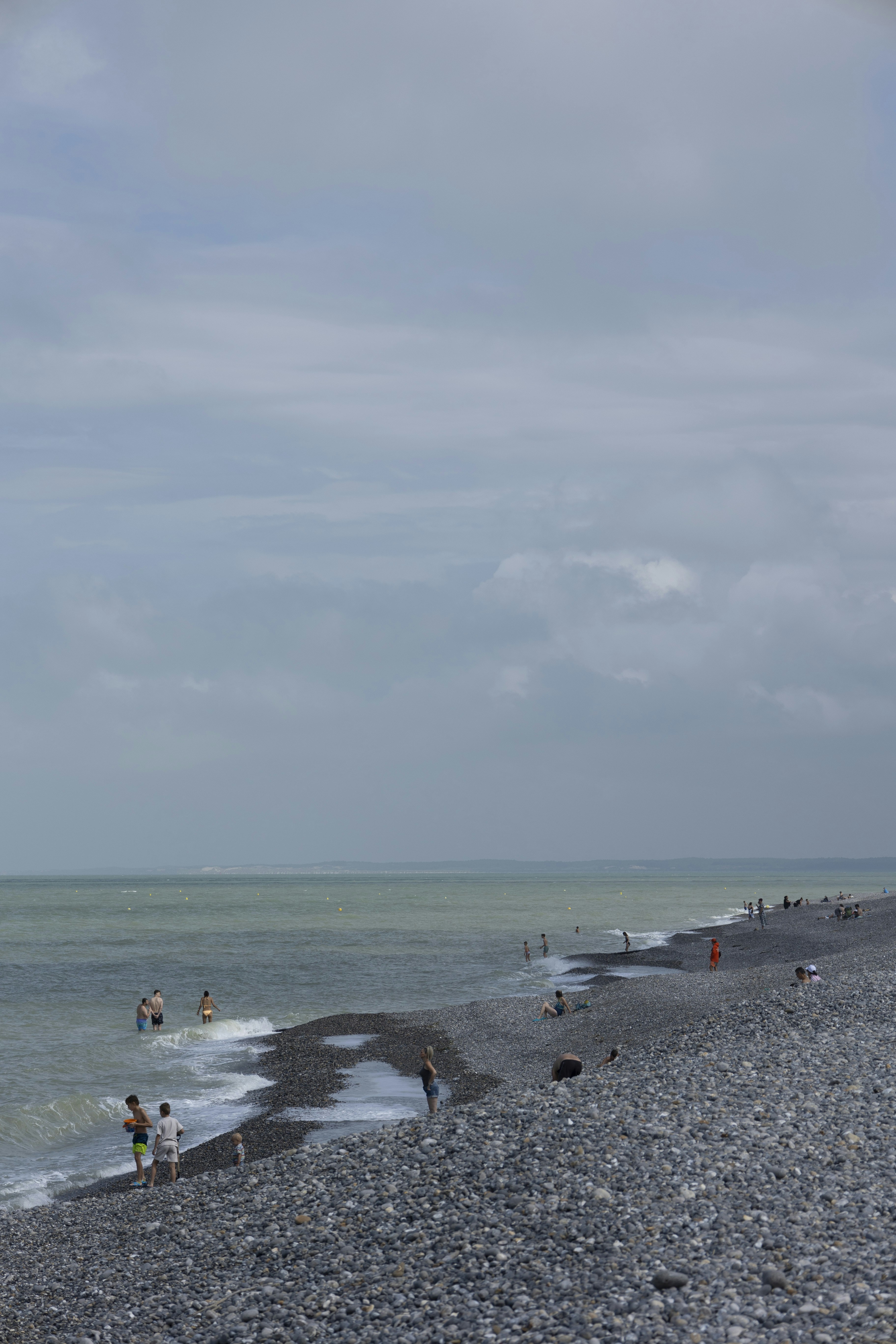 People swim and relax on a rocky beach.