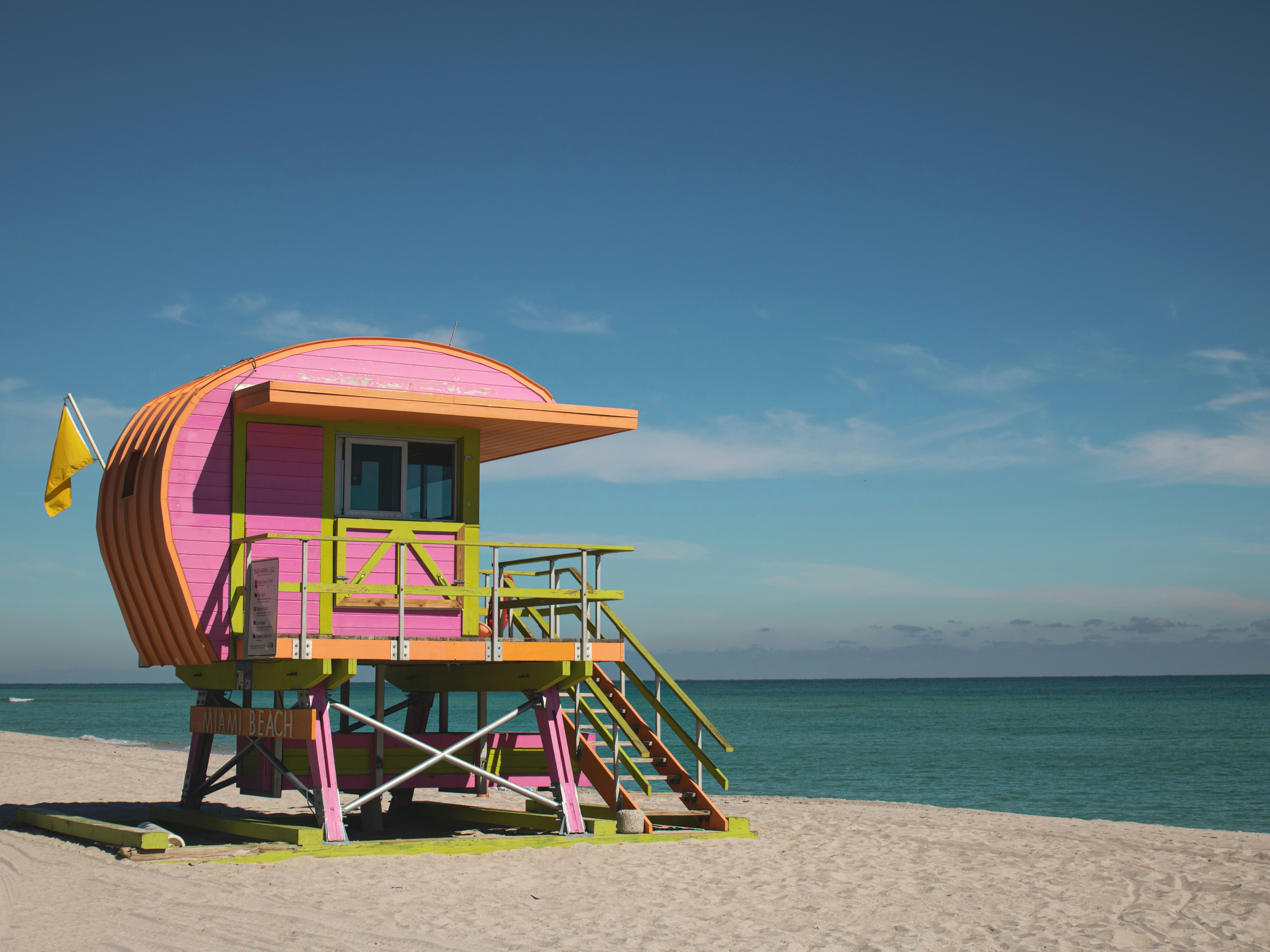 A colorful lifeguard tower stands on the sunny beach.
