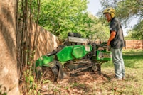 A worker operates a tree stump grinder.