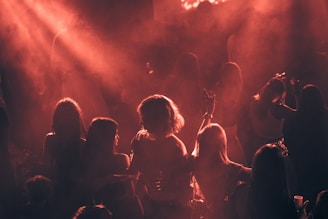 People dance in a smoky room with red lighting.