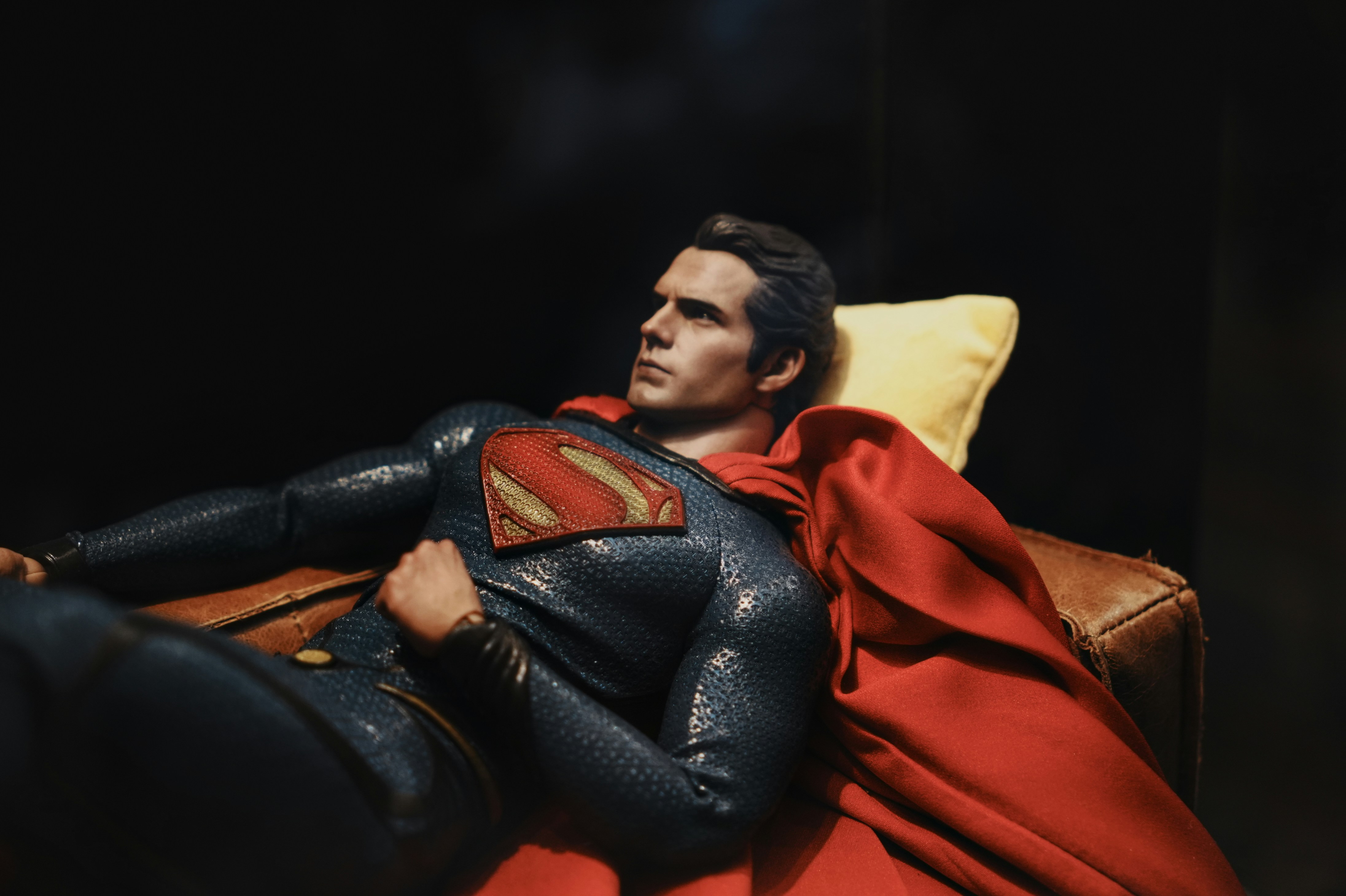 Superman relaxes on a couch, looking contemplative.