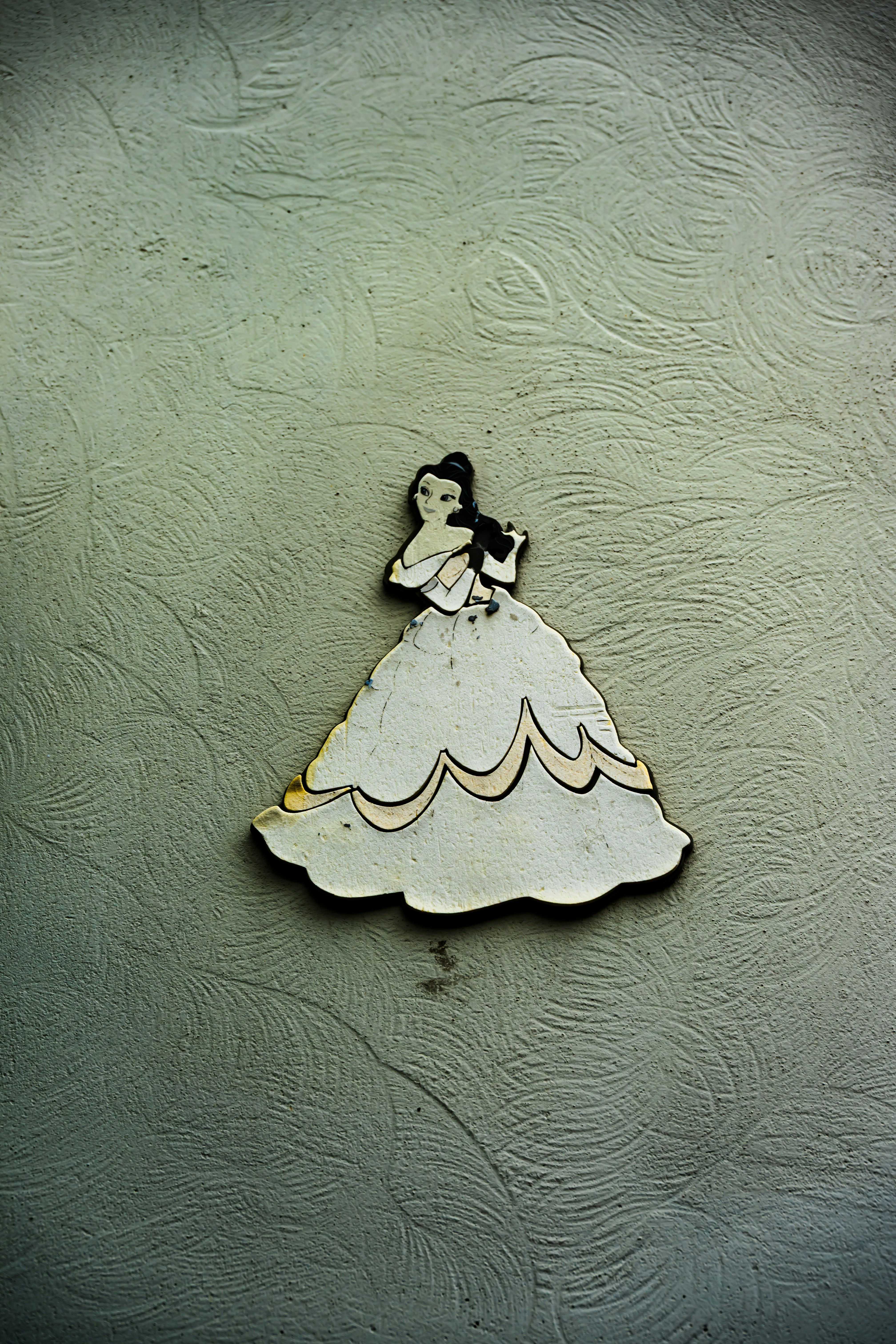 A princess decoration is fixed on a textured wall.