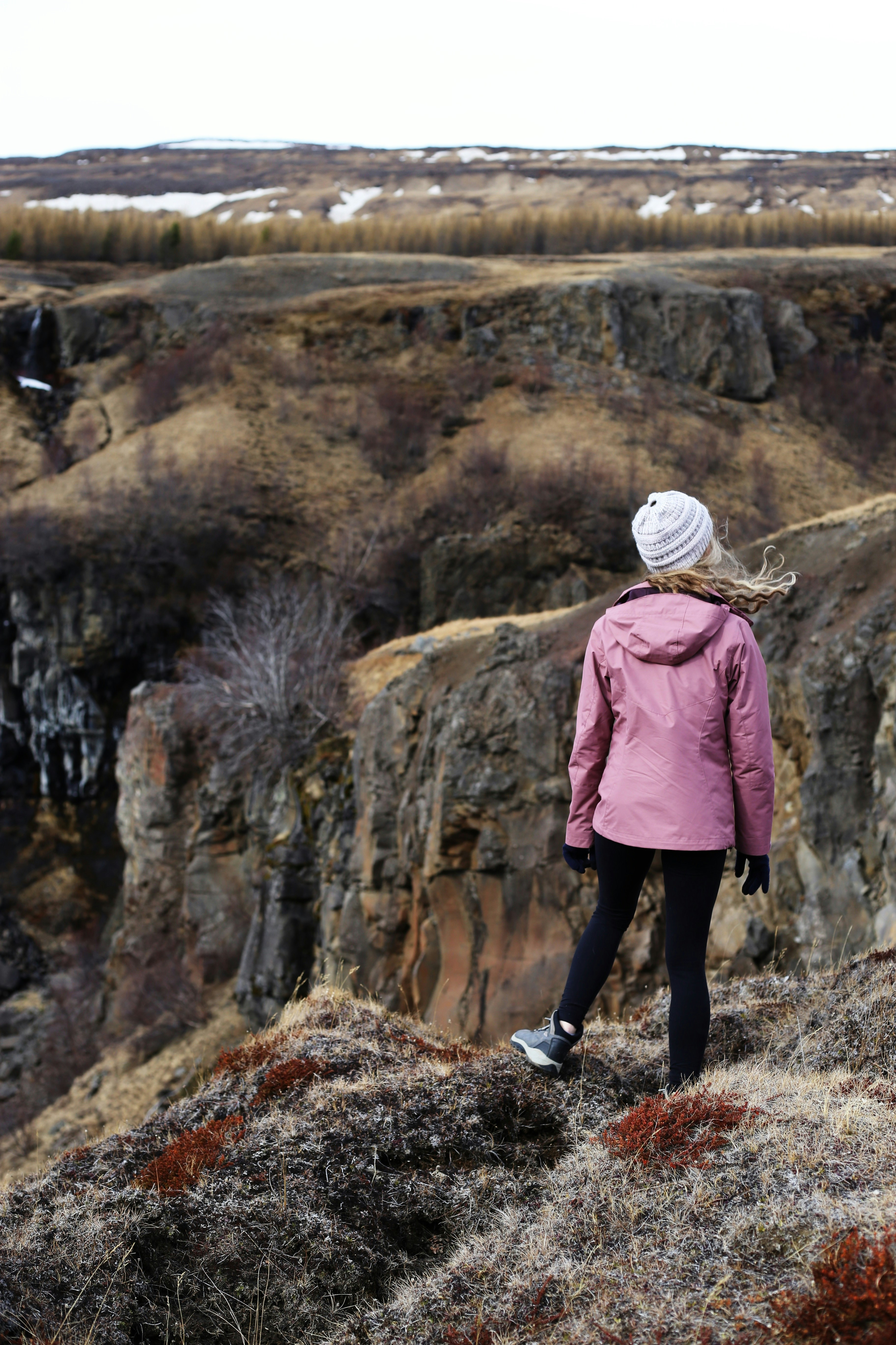 Woman stands on a cliff, gazing at the landscape.