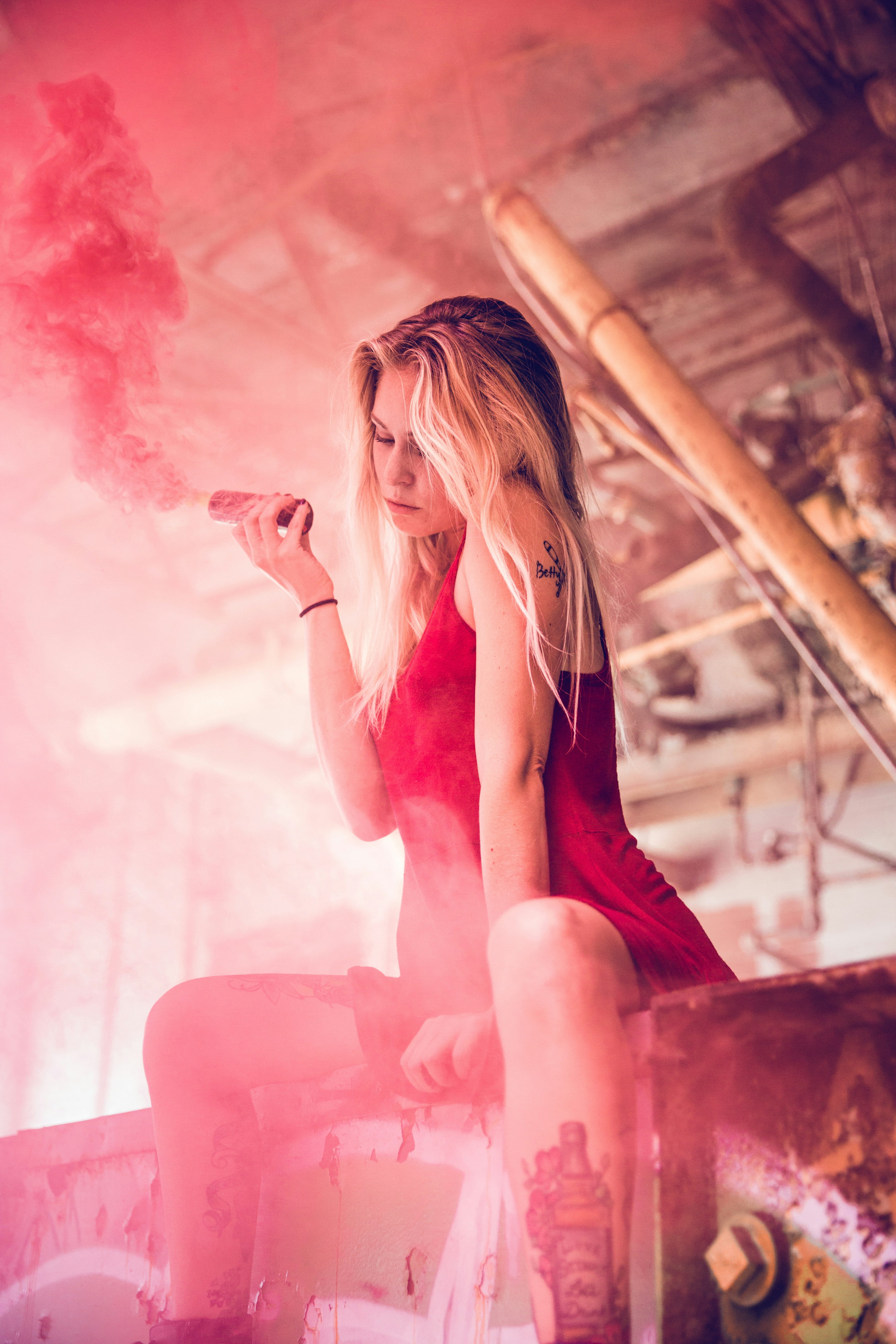 Blonde woman holds a red smoke bomb.