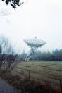 A radio telescope stands in a grassy field.