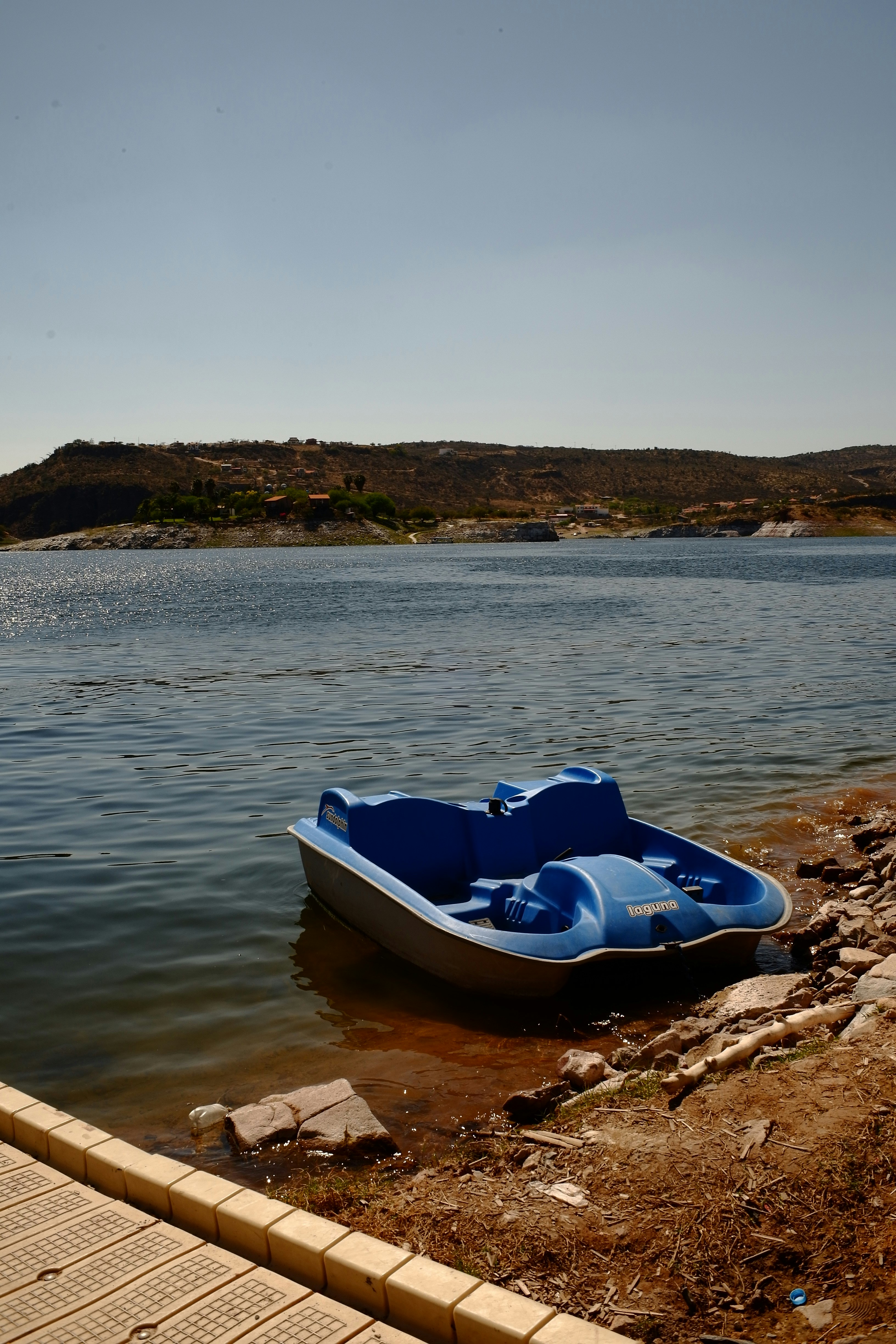 Ein blaues Paddelboot liegt am Seeufer.