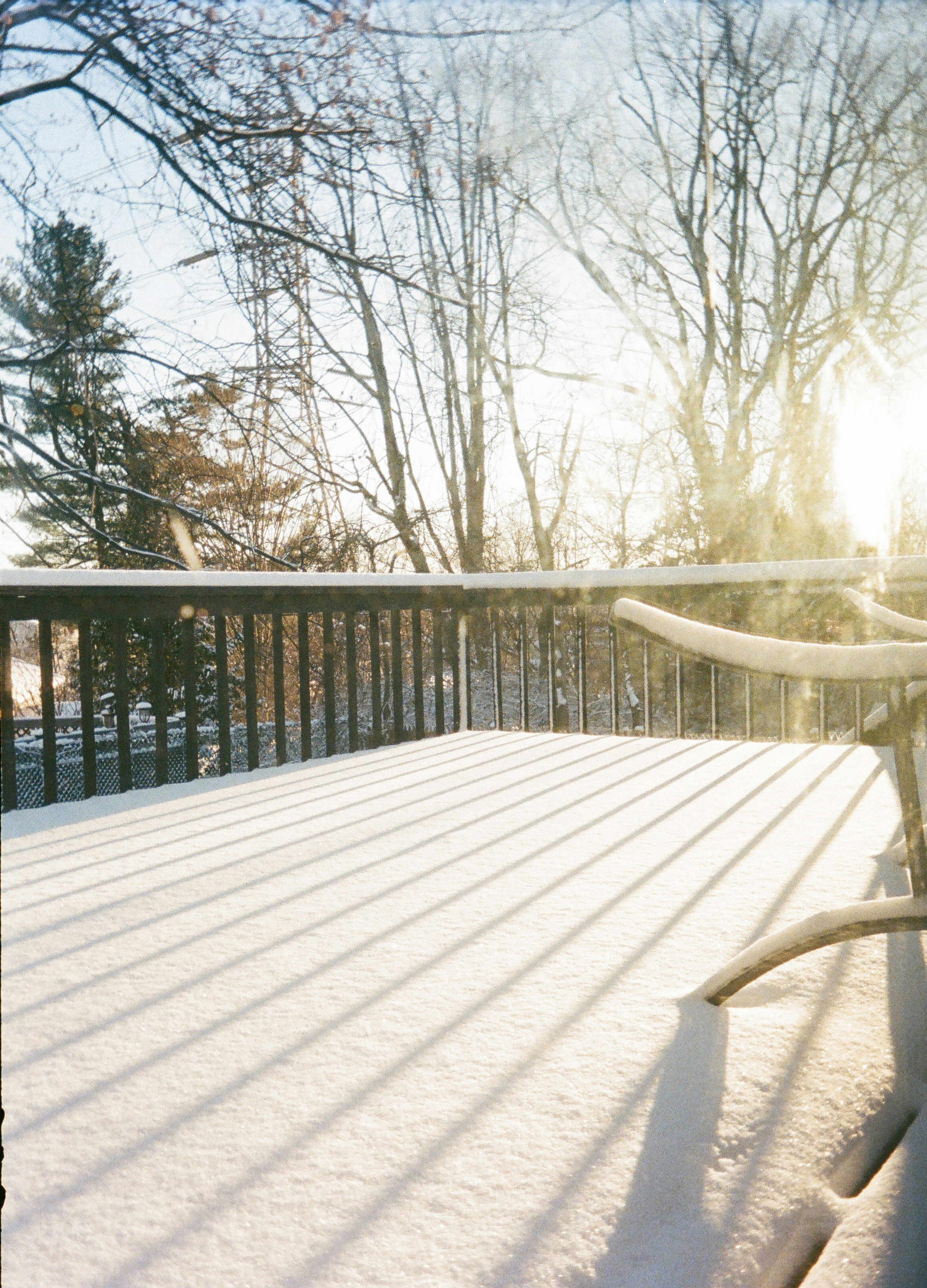 Snow blankets a deck on a sunny winter day.