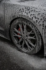 A car is covered in thick cleaning foam.