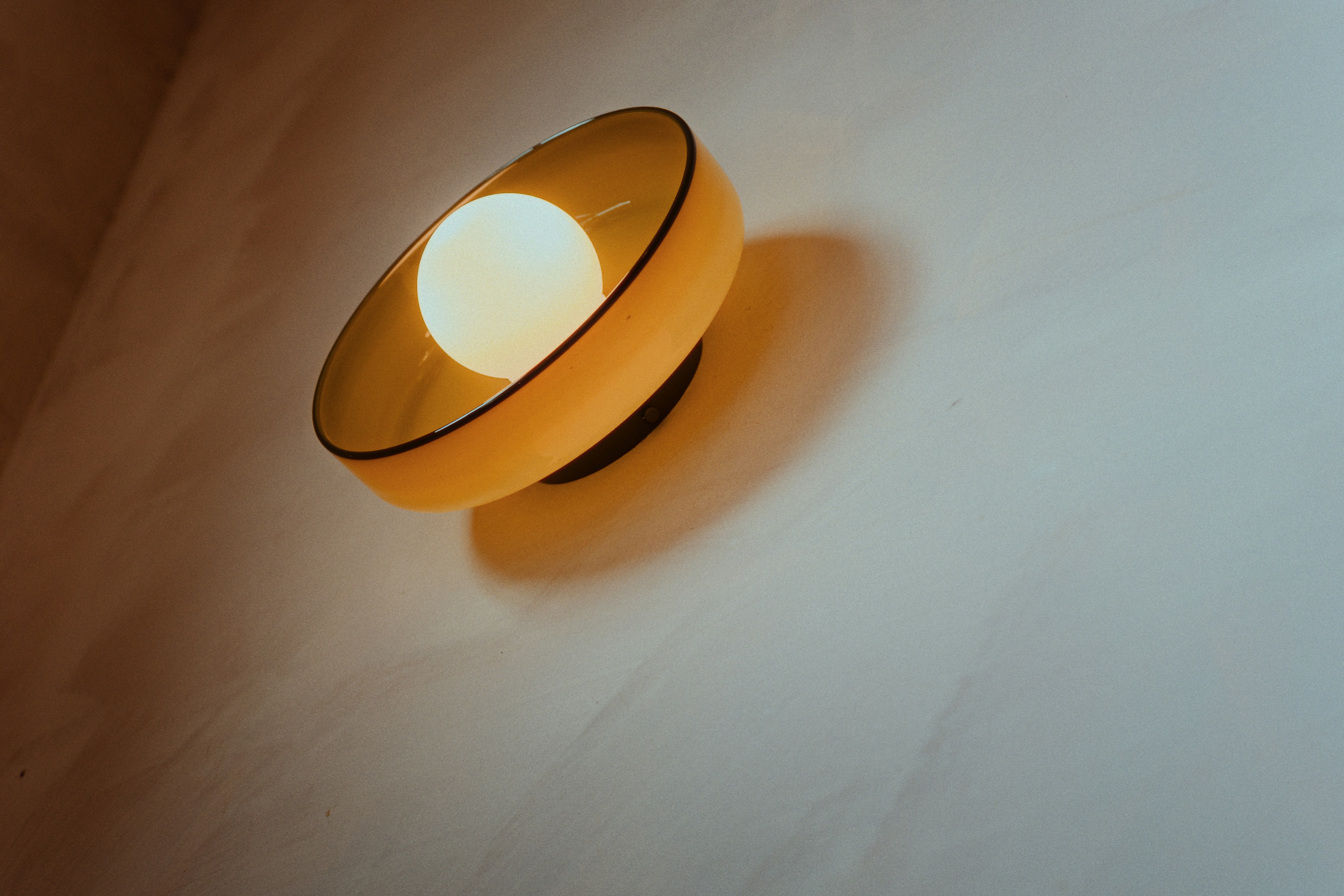 A yellow lamp illuminates a white wall.