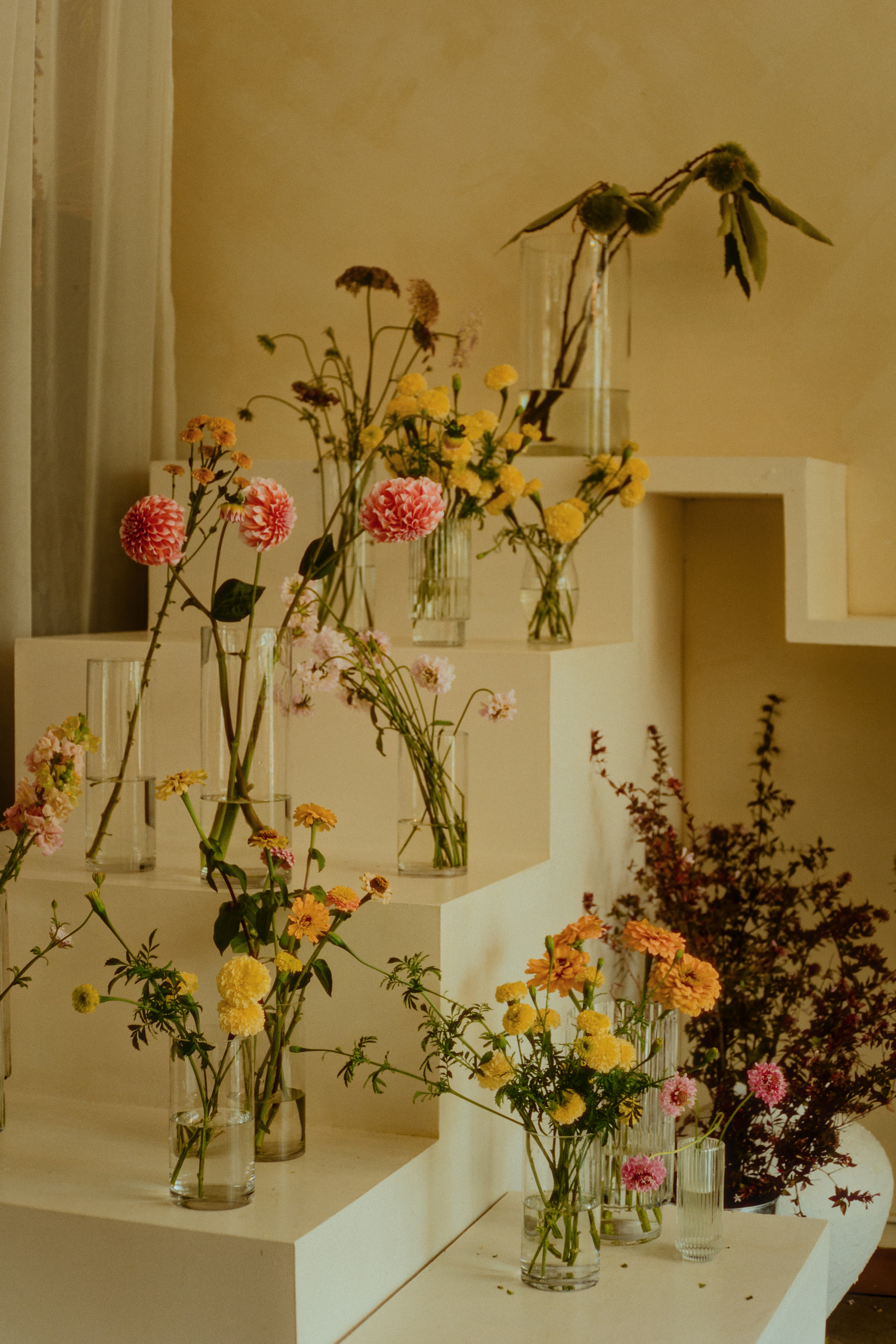 Flowers are arranged in vases on tiered steps.