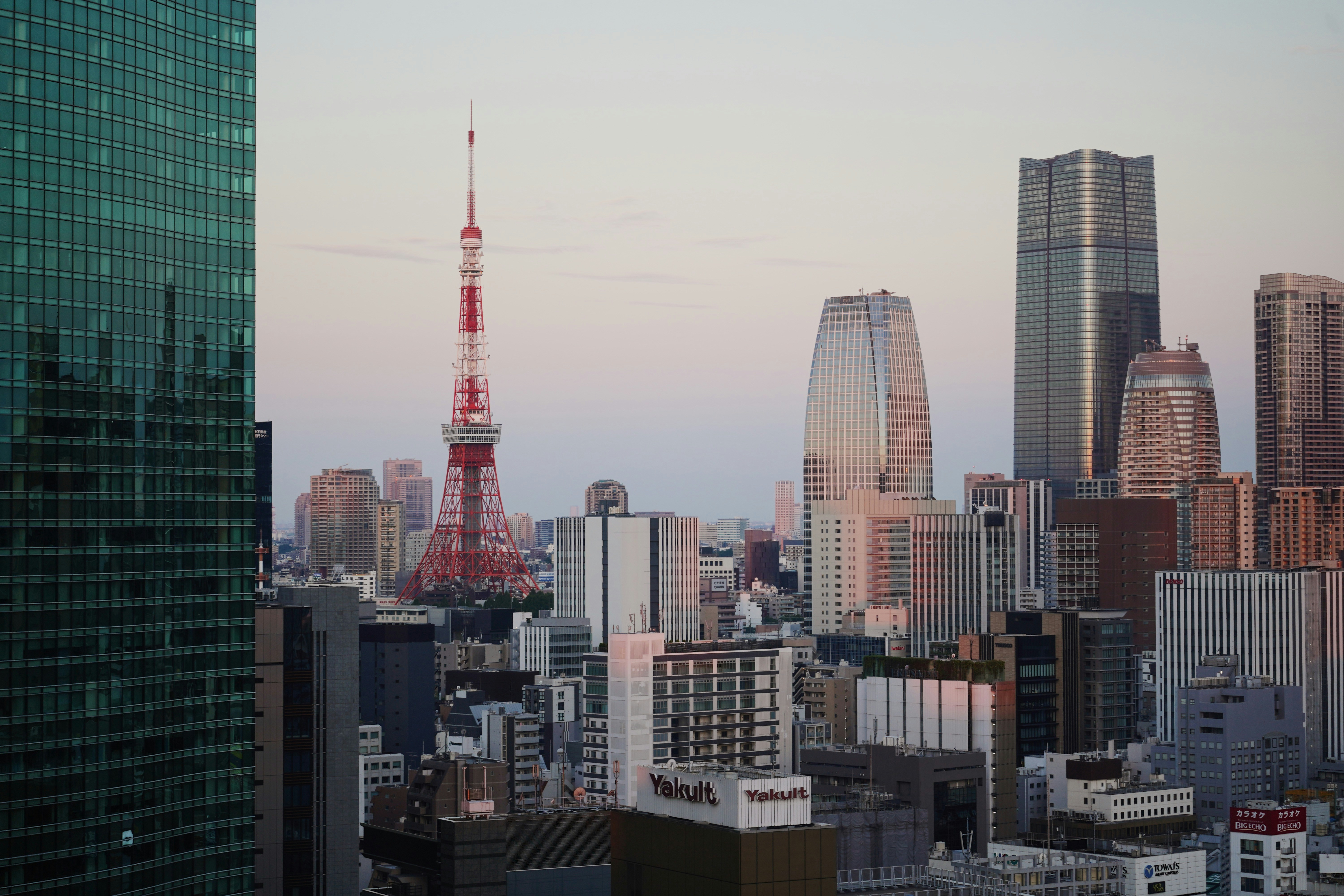 Tokyo tower stands among city skyscrapers.
