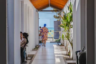 People walk down a long, light-filled corridor.