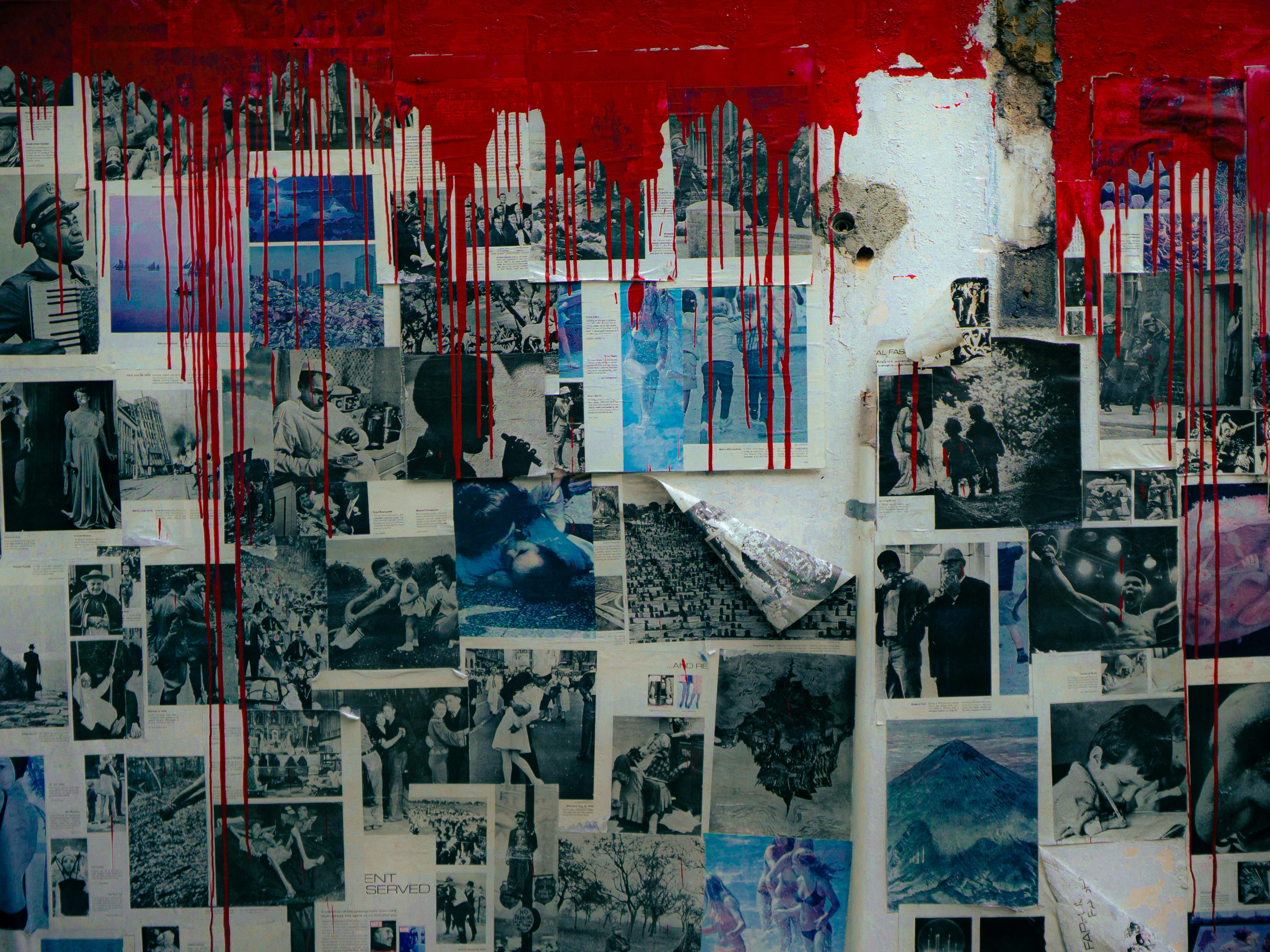 Photos on a wall with red paint dripping.