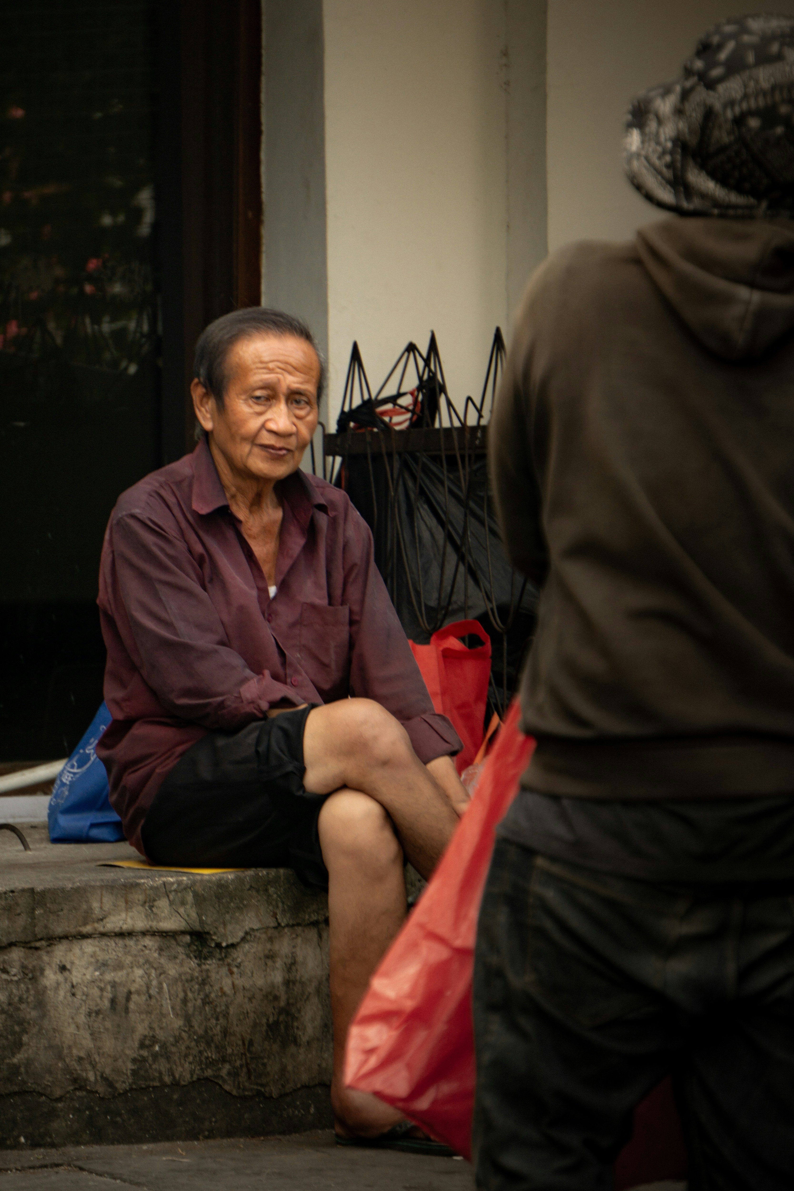 An older man sits outdoors and smiles.