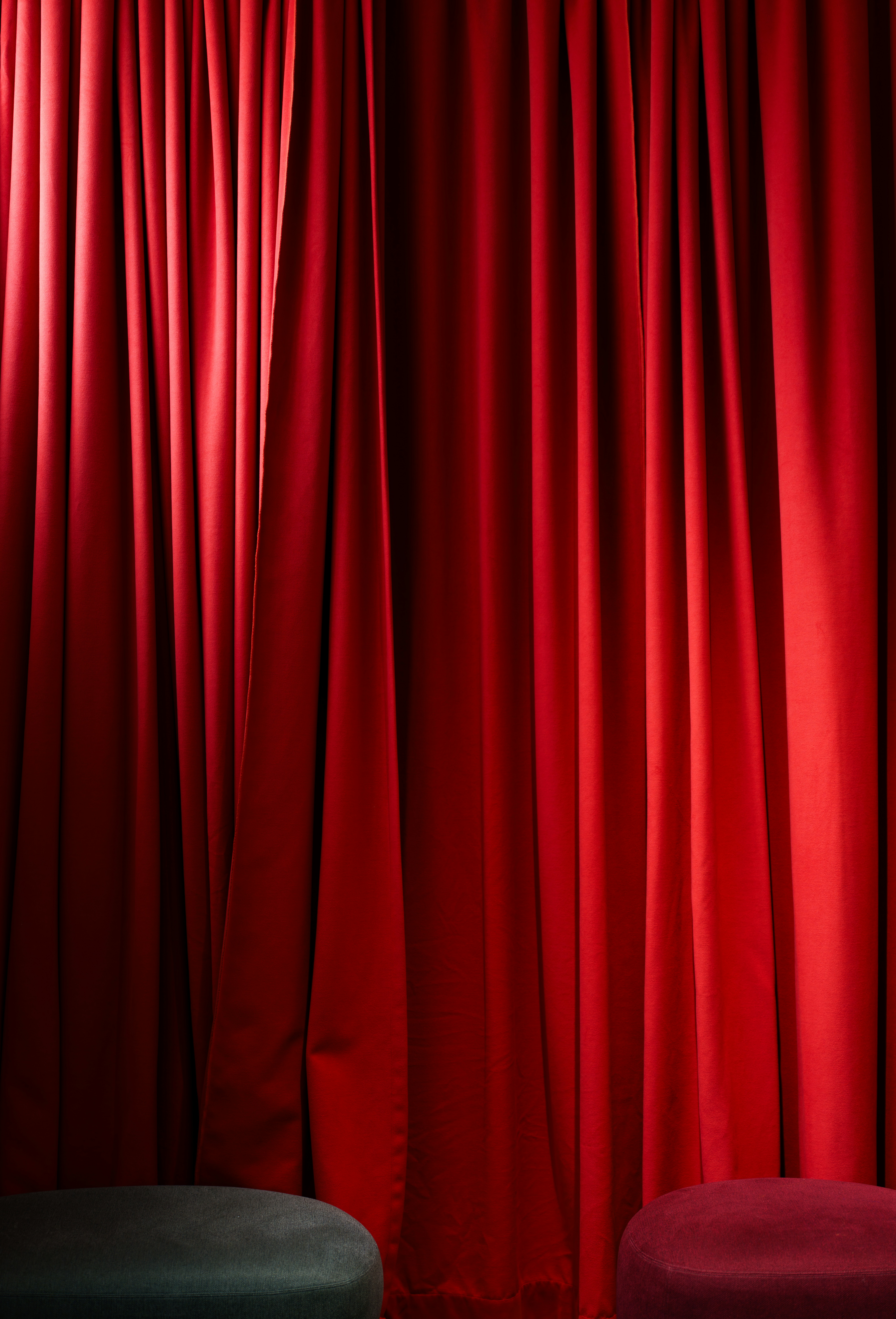 Red curtains and two small stools are featured.