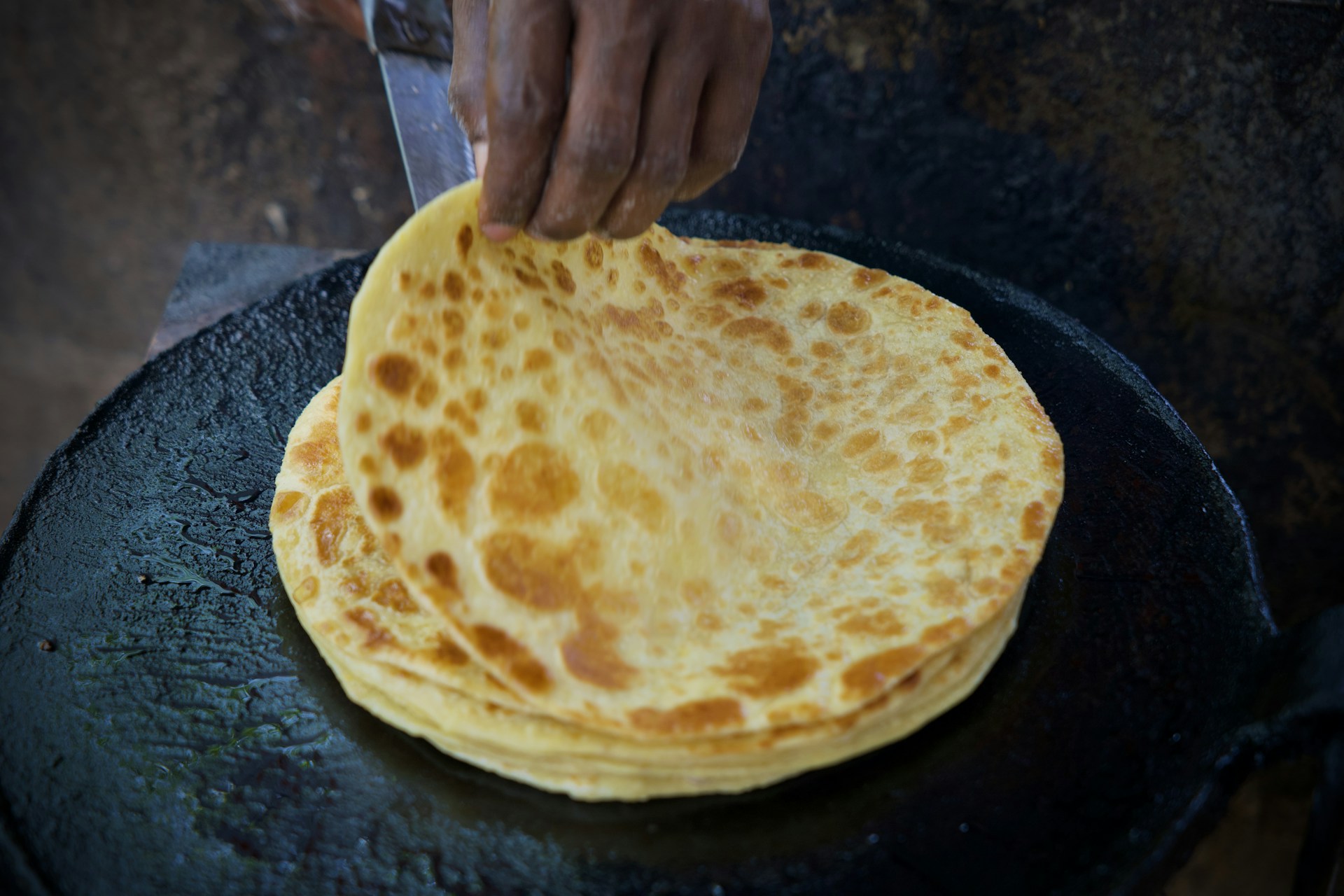 Cooking paratha on a hot, flat griddle.