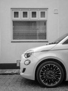 A white car is parked in front of a window.