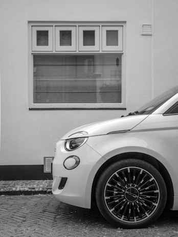 A white car is parked in front of a window.