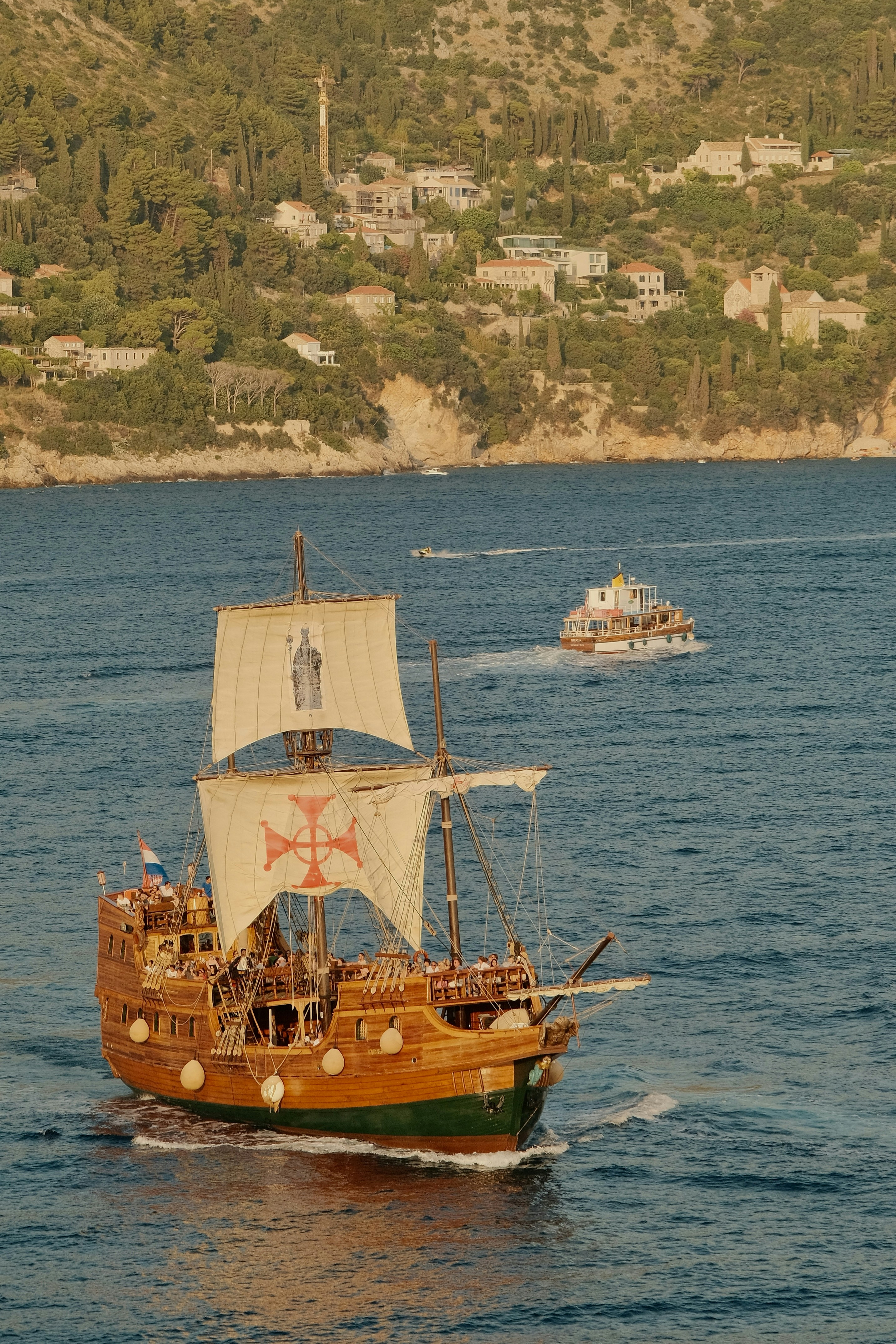 A wooden sailing ship cruises on the sea.