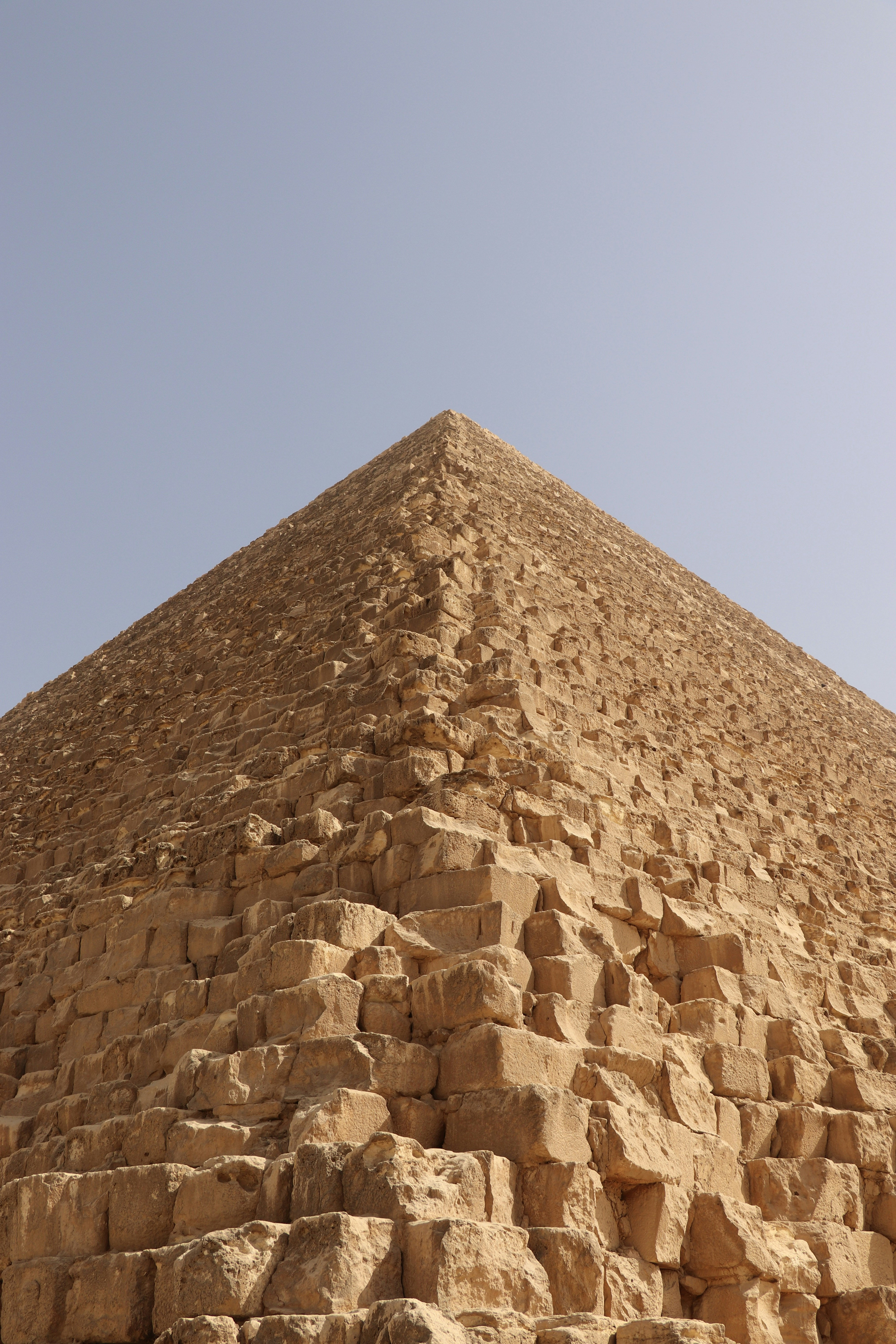 A pyramid rises against a clear blue sky.