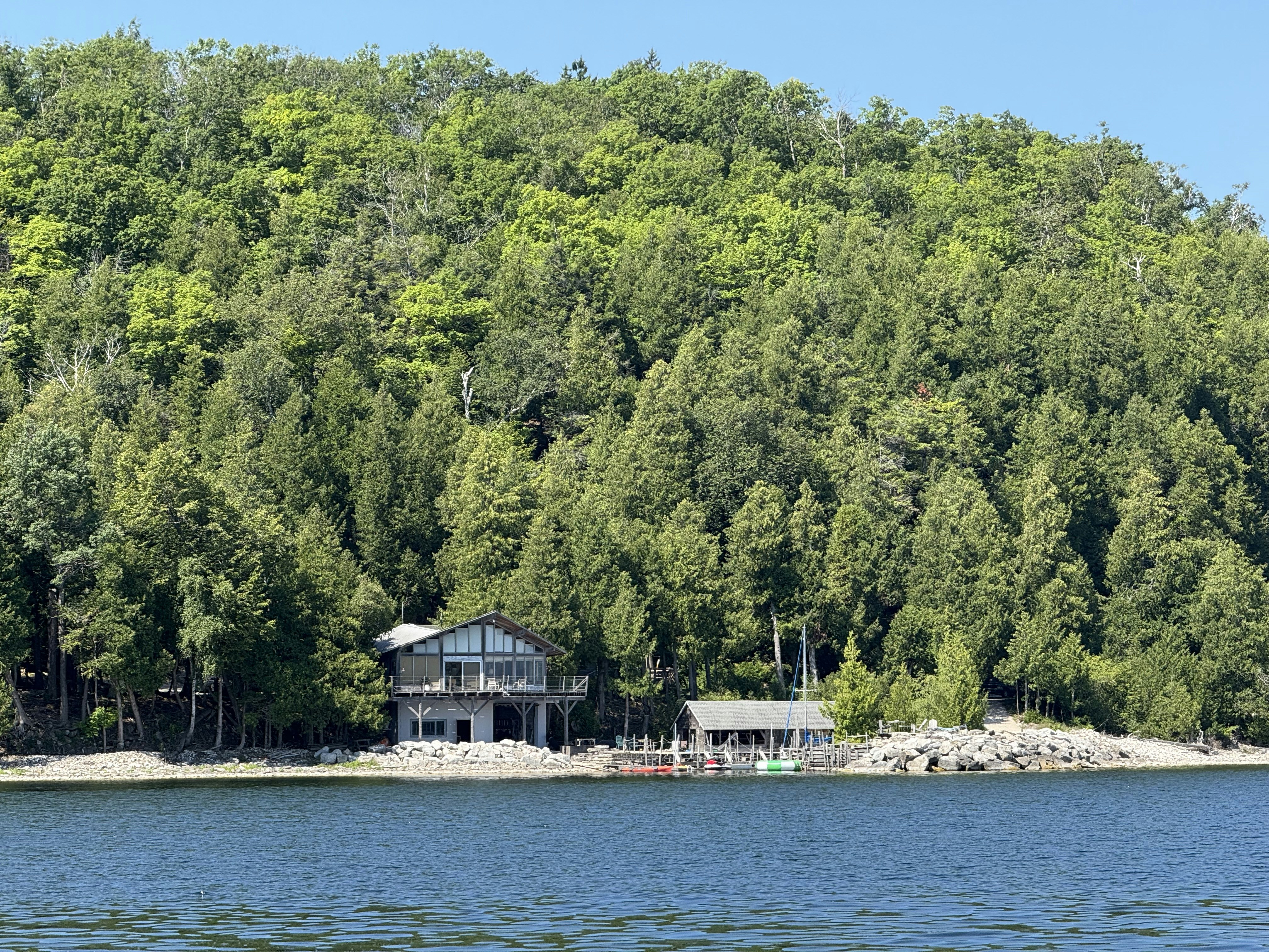 Houses sit near the lake in a wooded area.
