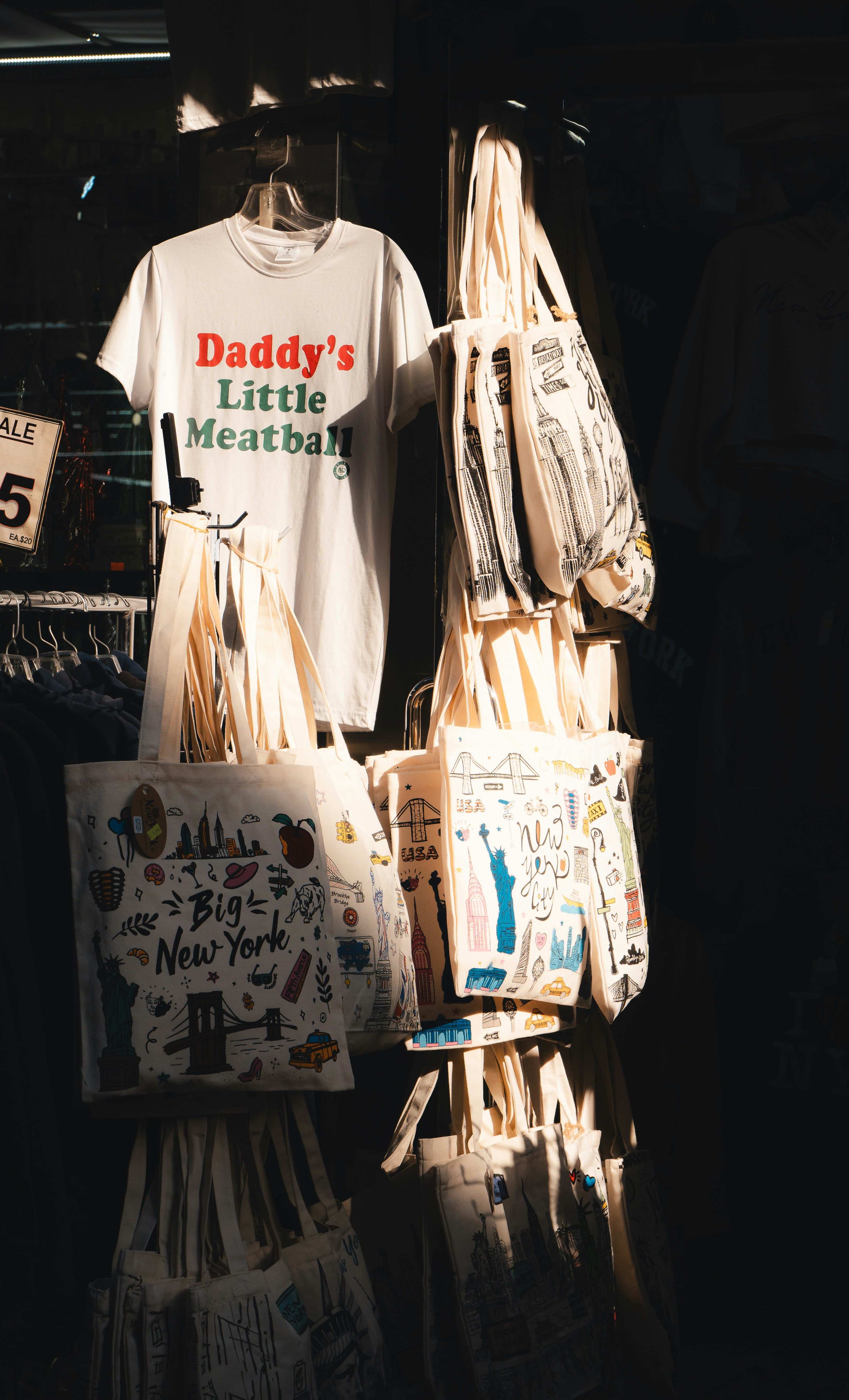 Shirts and bags are for sale in a store.