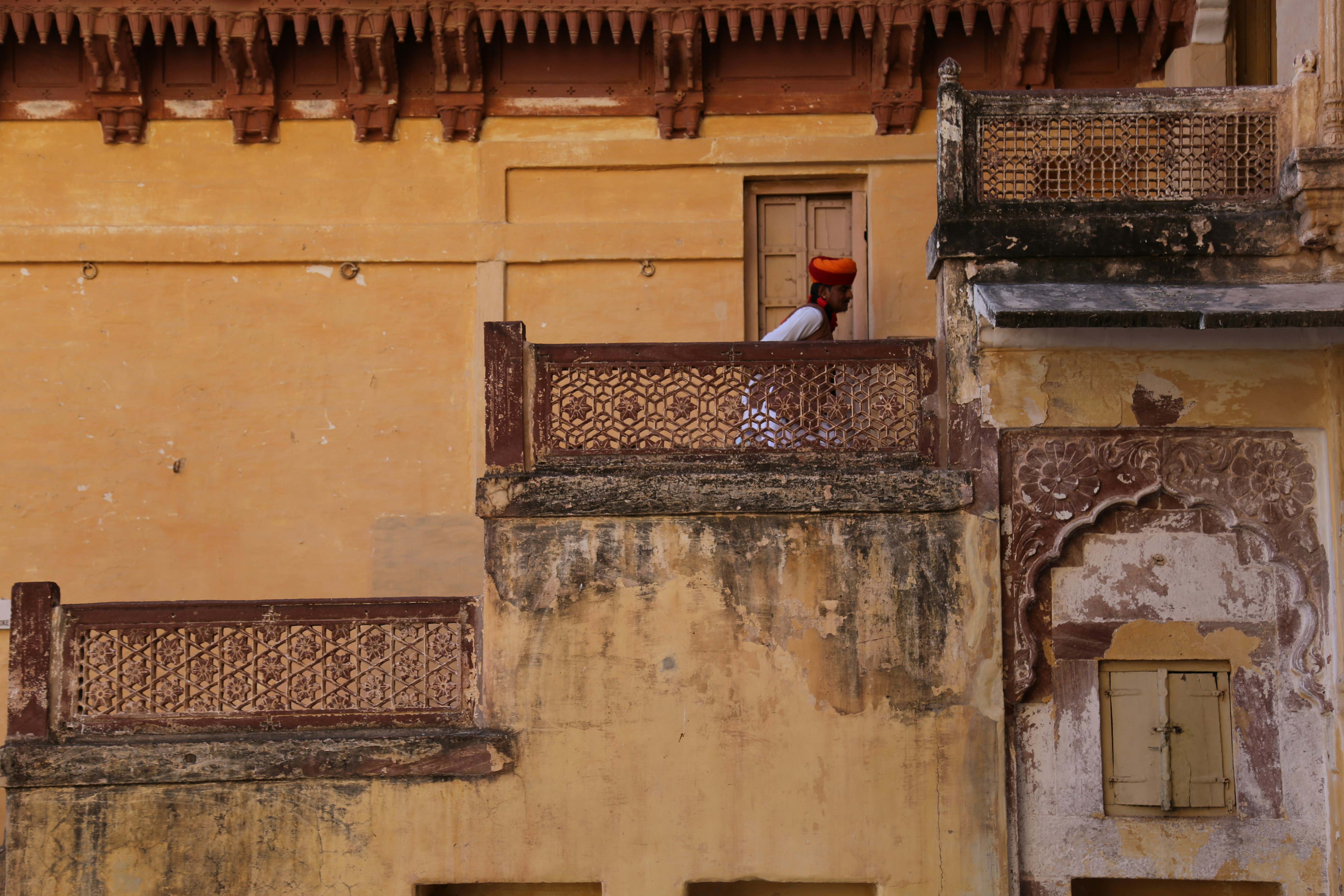Man in turban looks from a balcony.