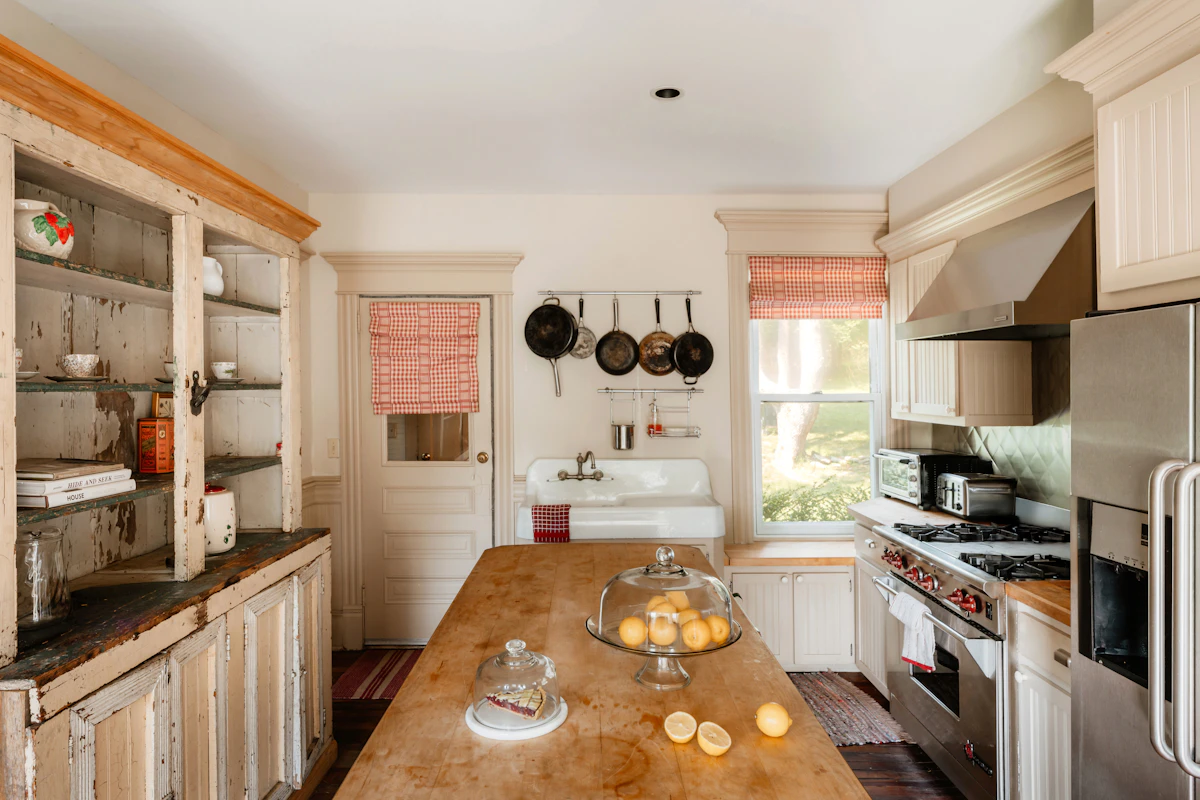 Cocina con estantes abiertos, cacharros colgados y mesa de madera