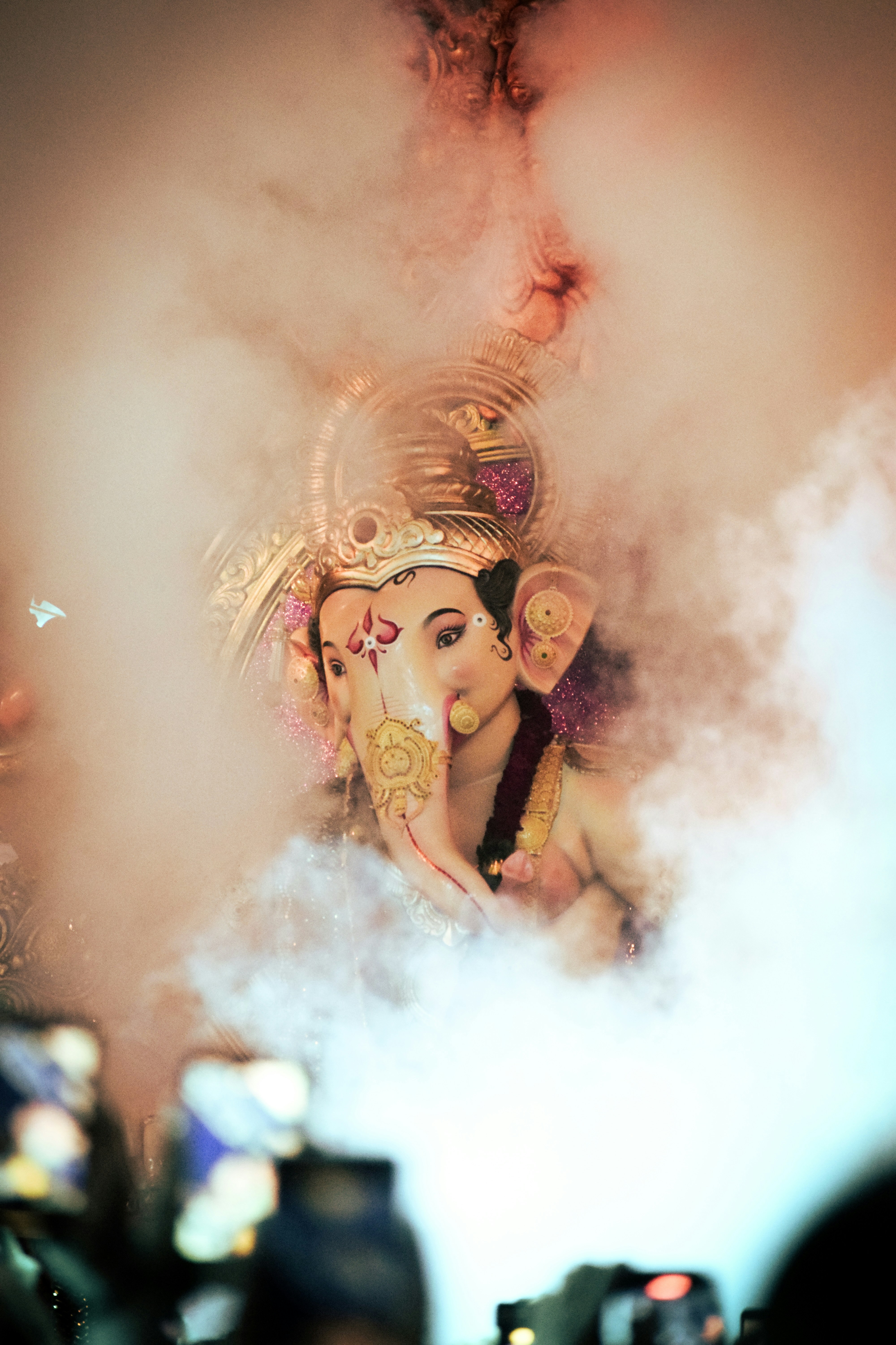 Lord ganesha surrounded by smoke during a festival.