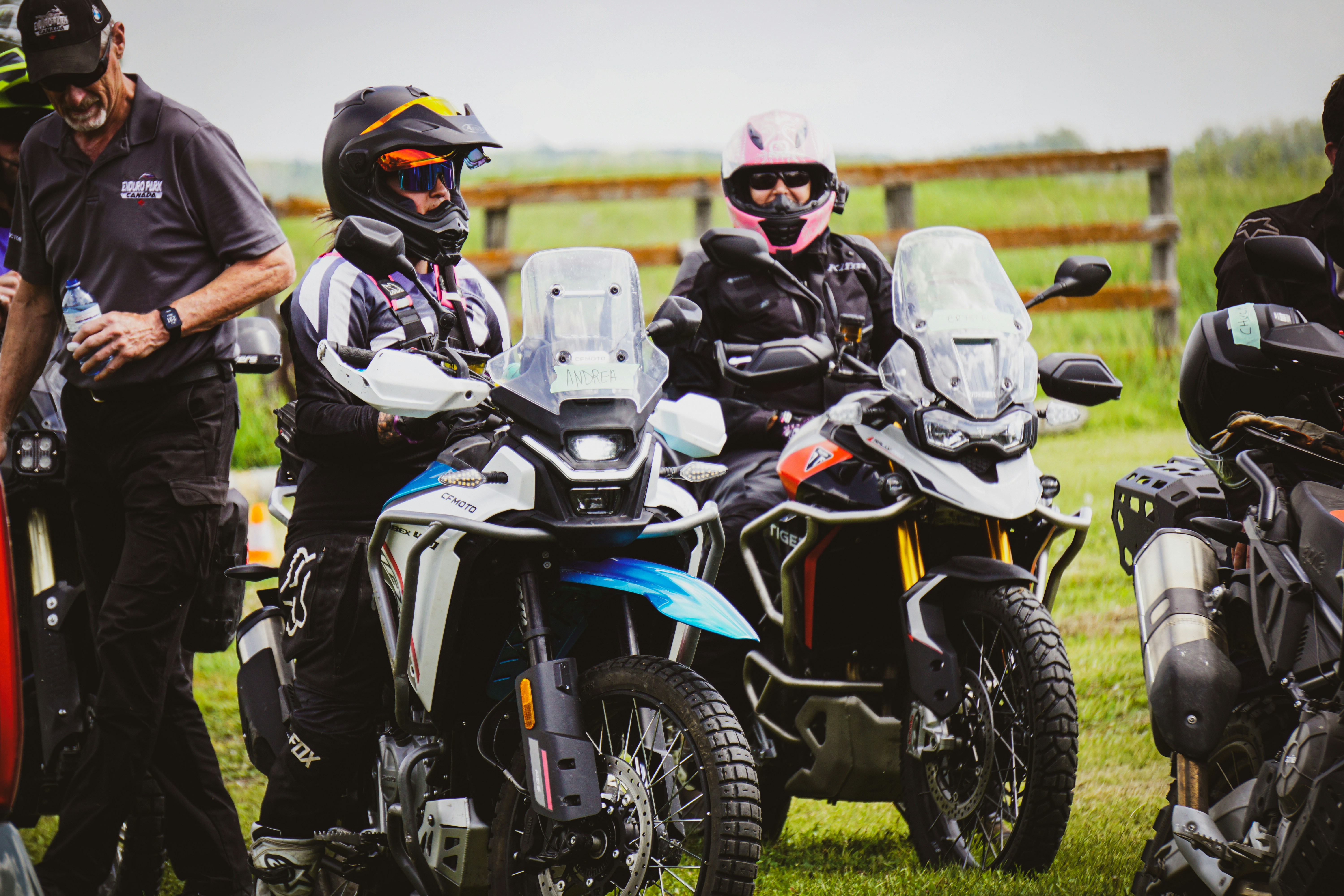 Motorcyclists stand near their adventure bikes.