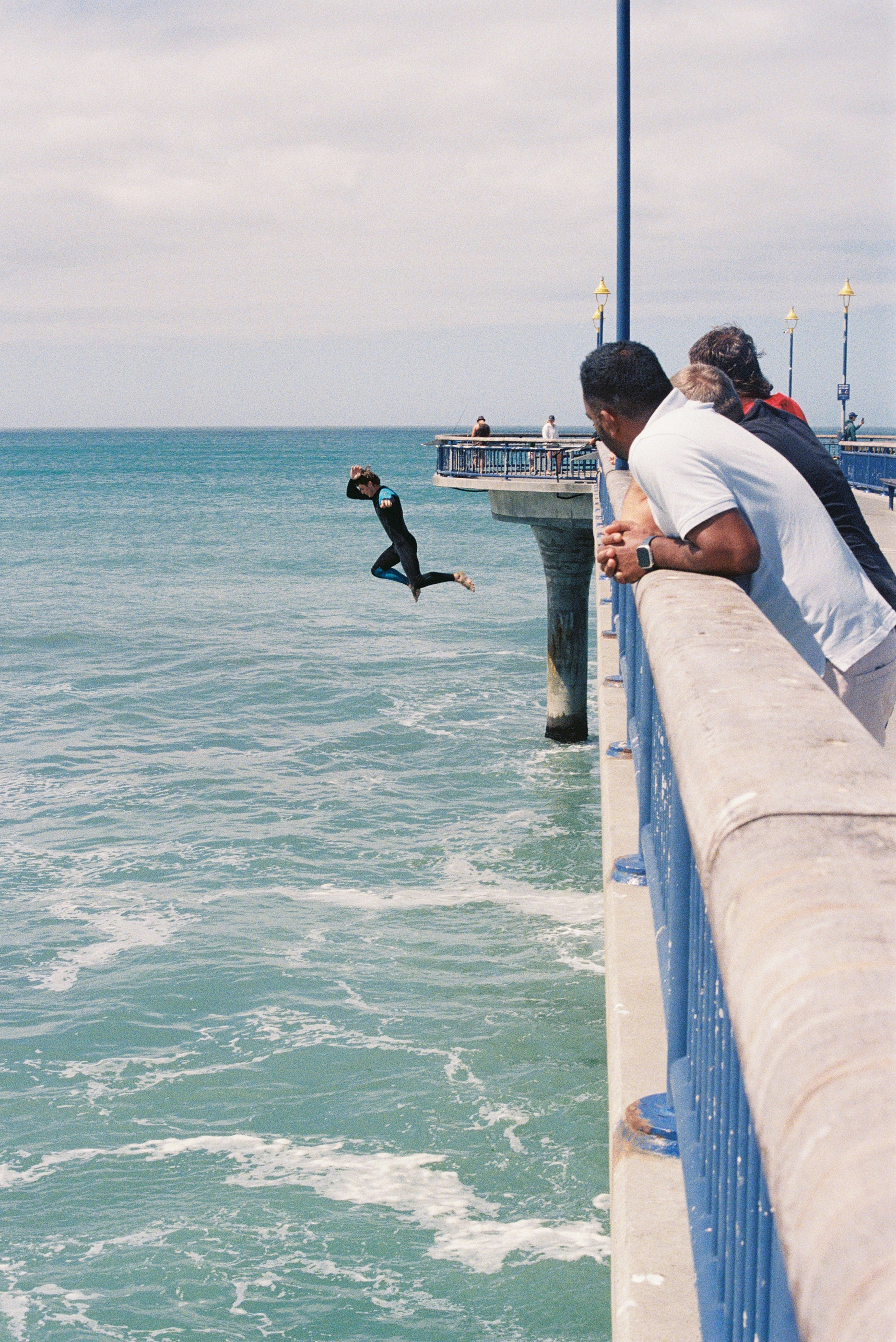 A person jumps from a pier into the ocean.
