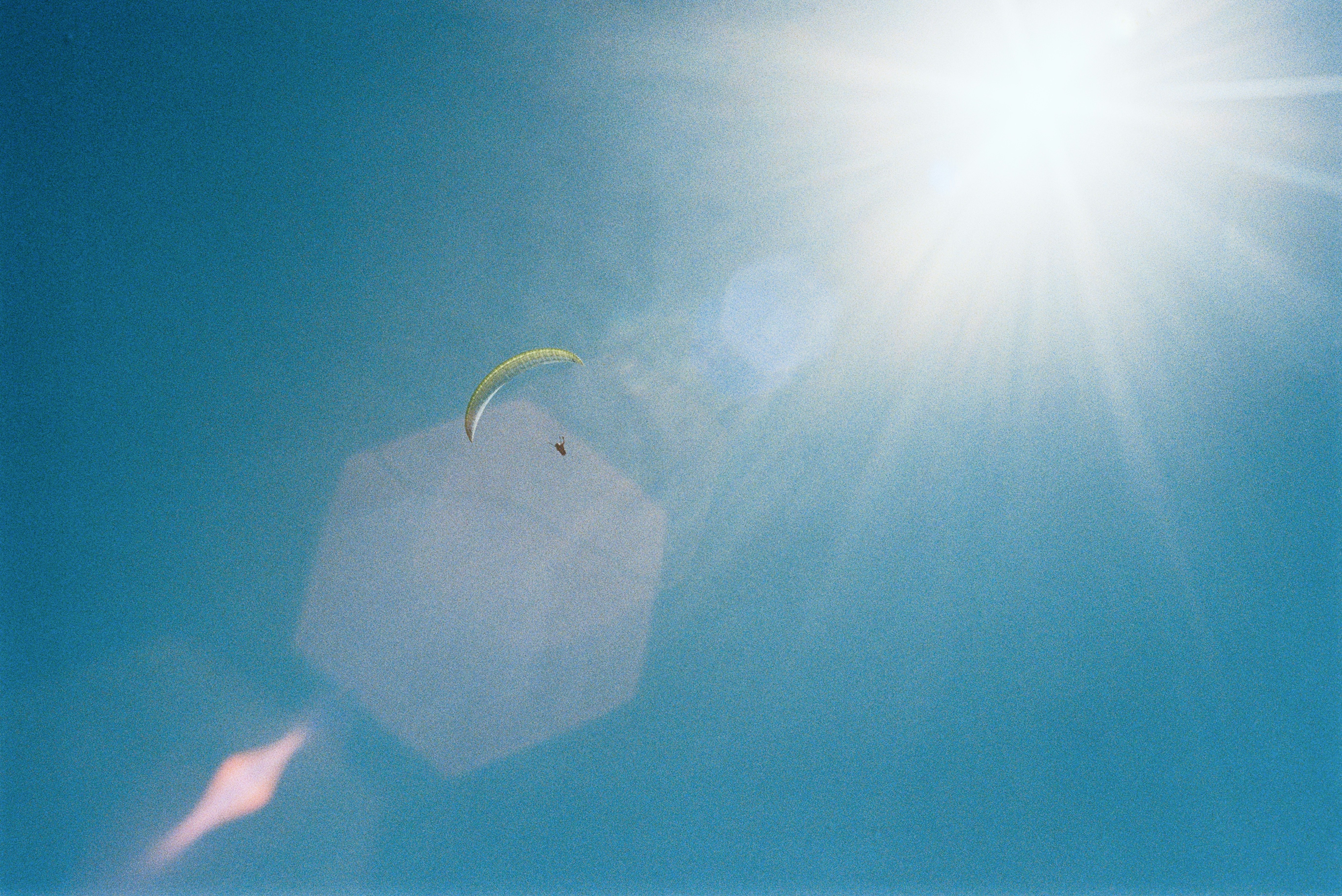 Paraglider soars in the bright, sunny sky.