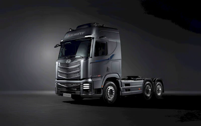 A modern semi-truck is pictured against a dark backdrop.