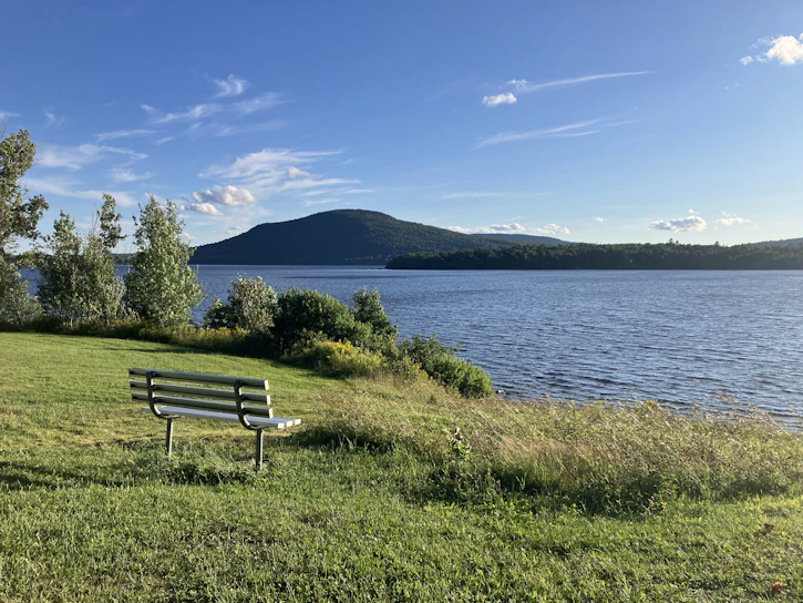 A bench overlooks a peaceful lake and mountain.