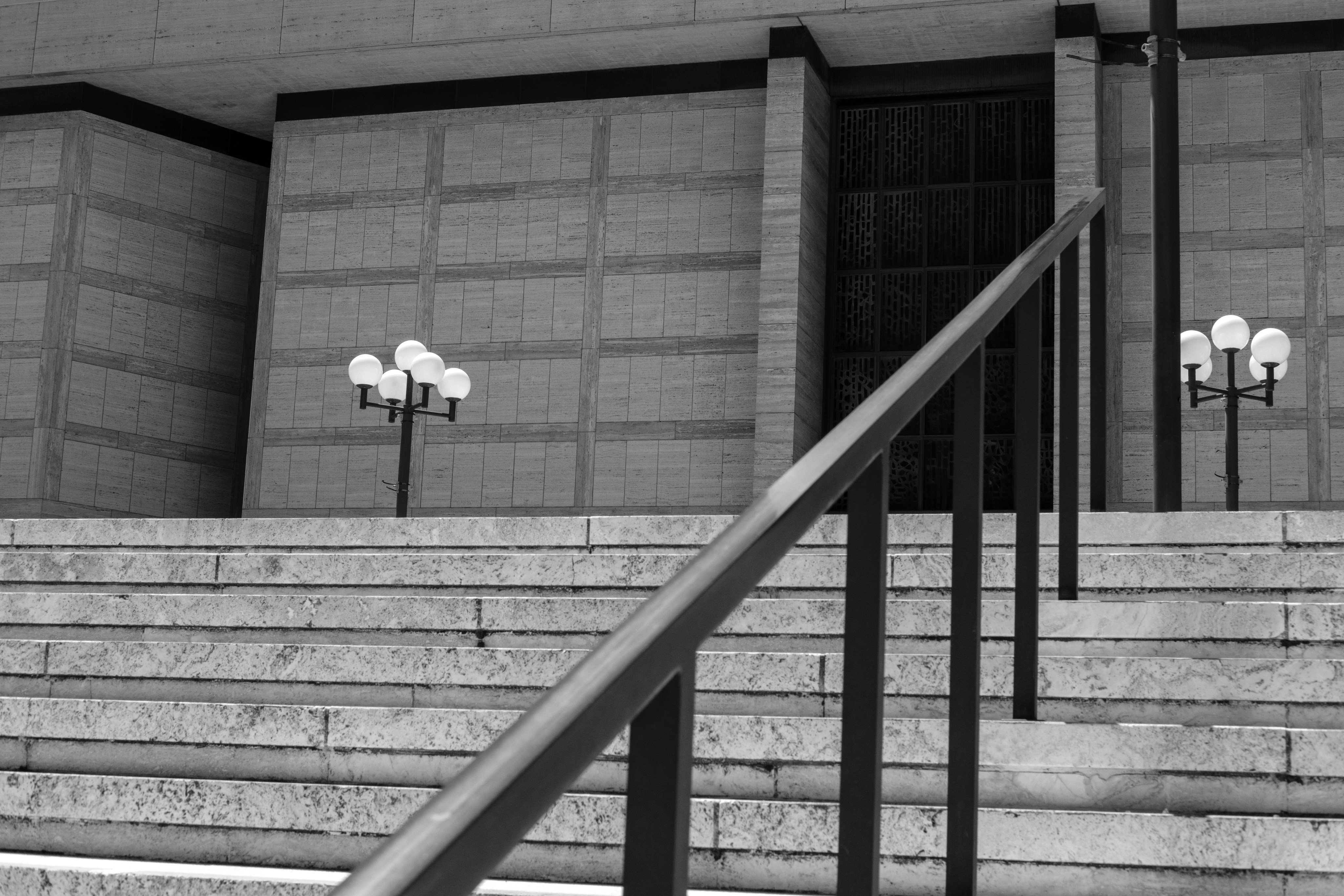 A building's stairs and handrail in black and white.