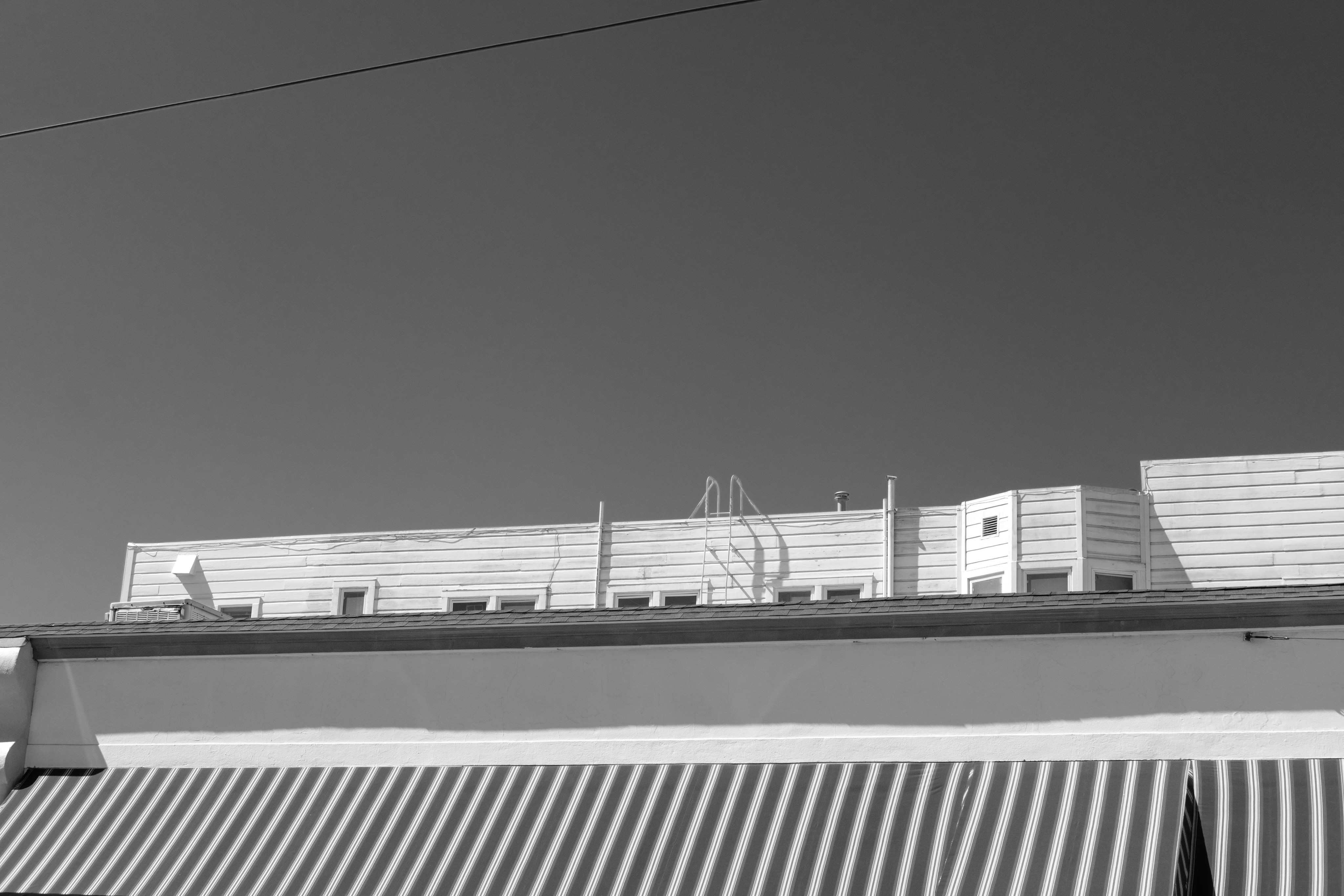 A building with a striped awning and plain sky.