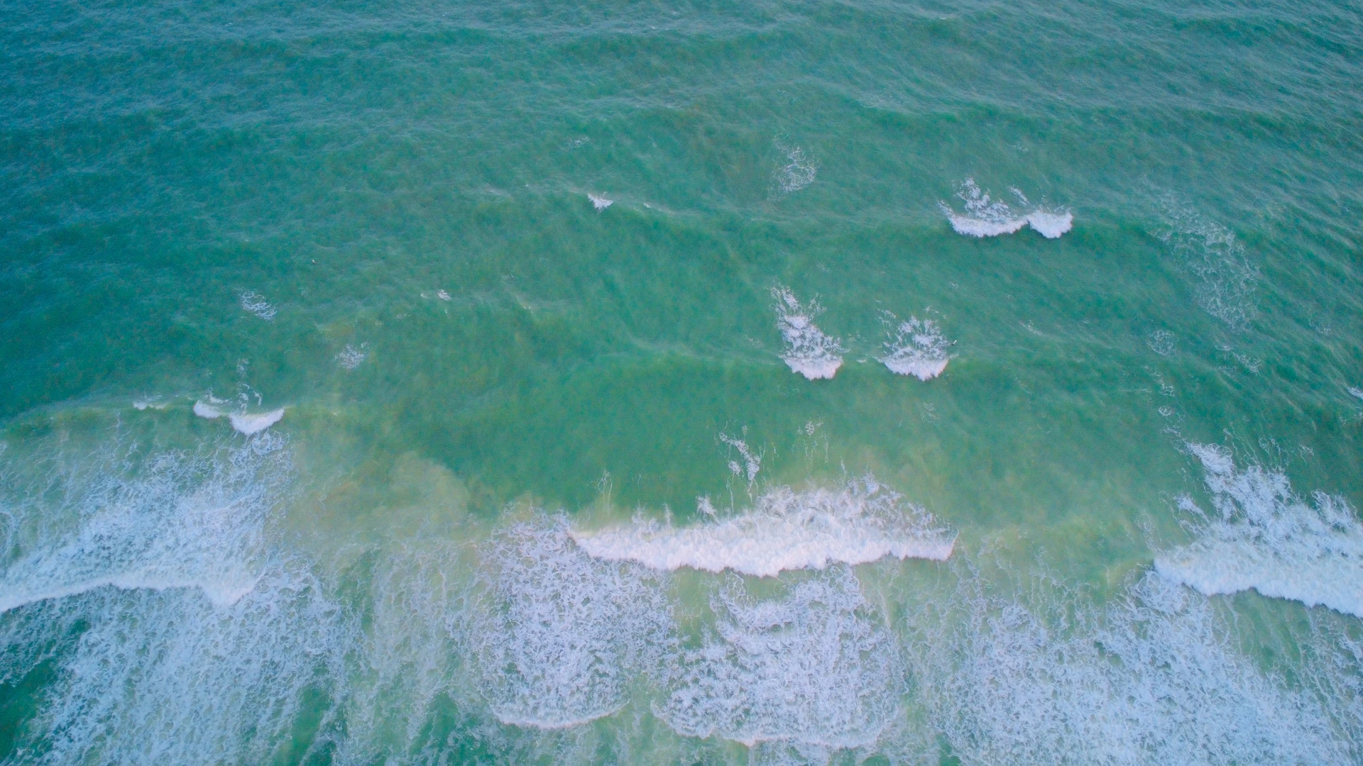 Waves crash upon the shoreline, a turquoise ocean.