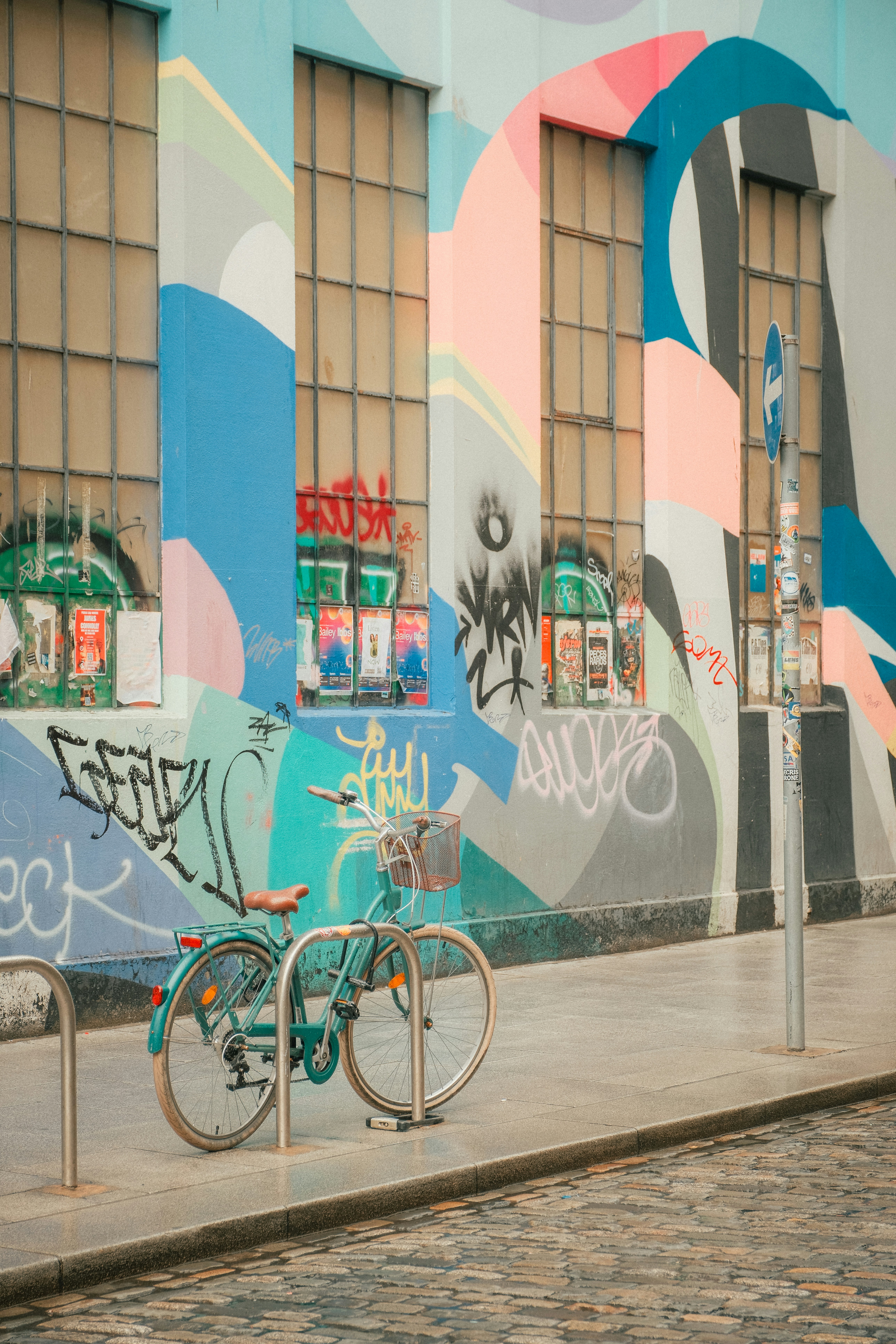 A bicycle sits by a colorful, graffiti-covered wall.