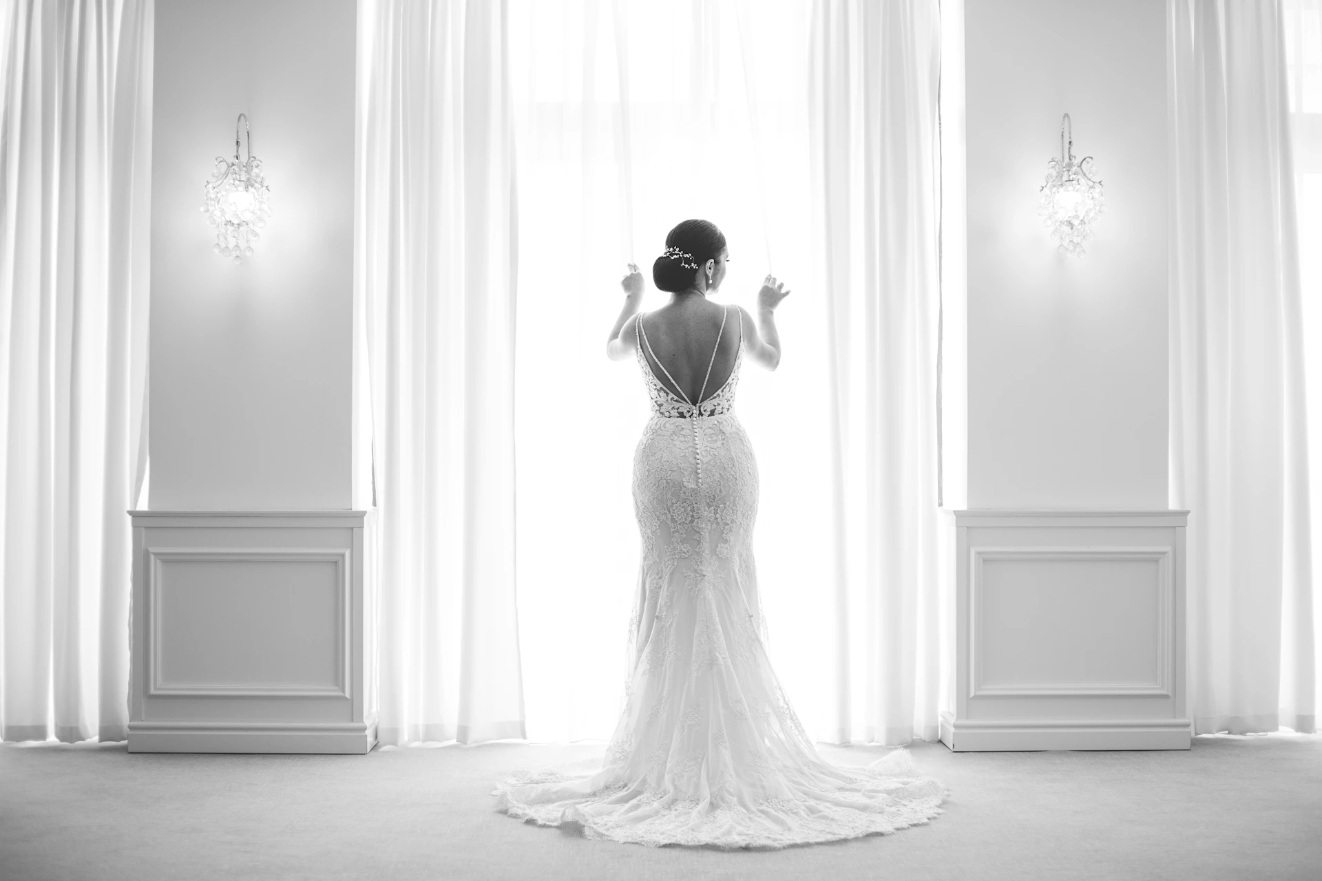 A bride gazes out a bright window.